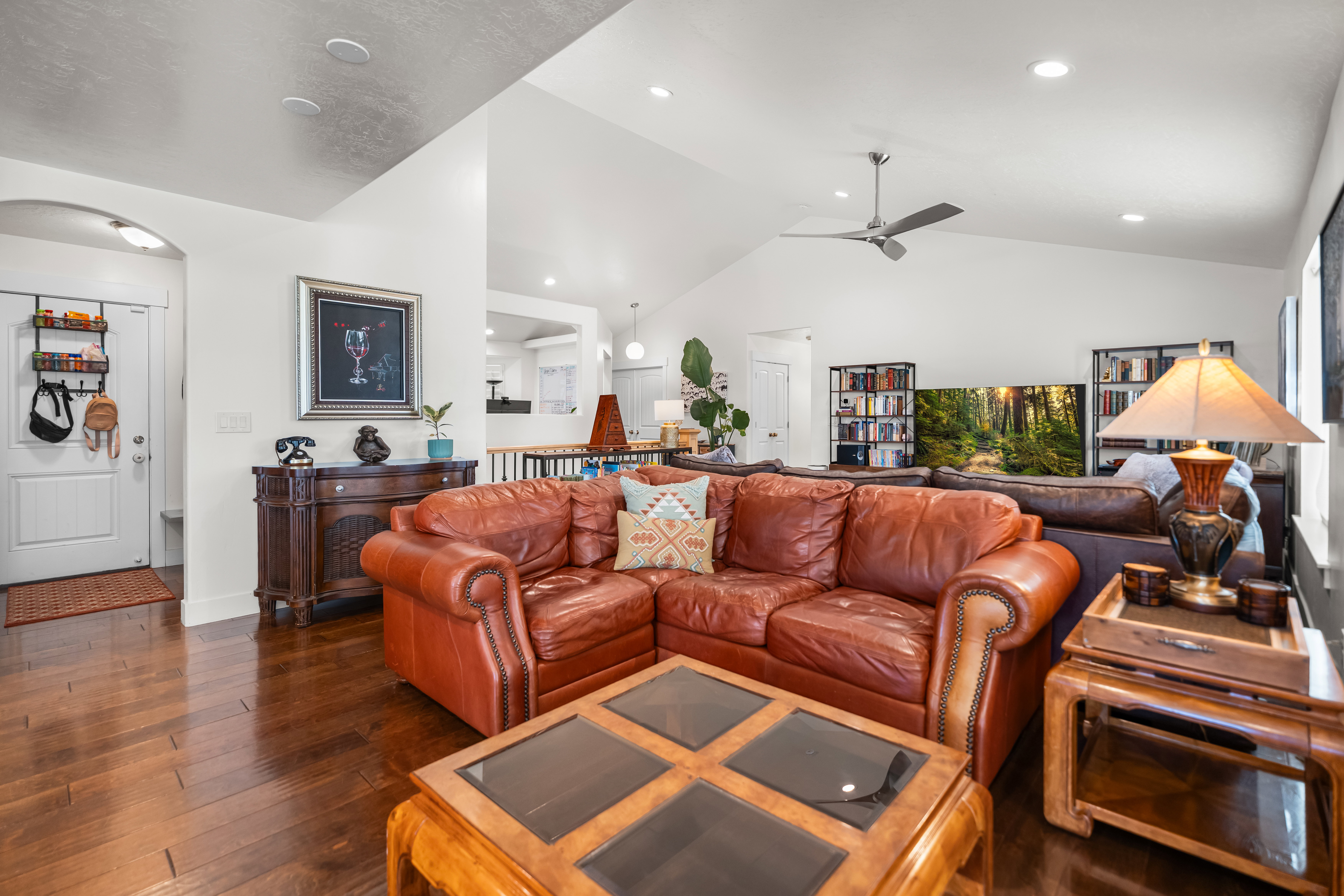 Spacious living area featuring rich wood-finish flooring and a vaulted ceiling with recessed lighting