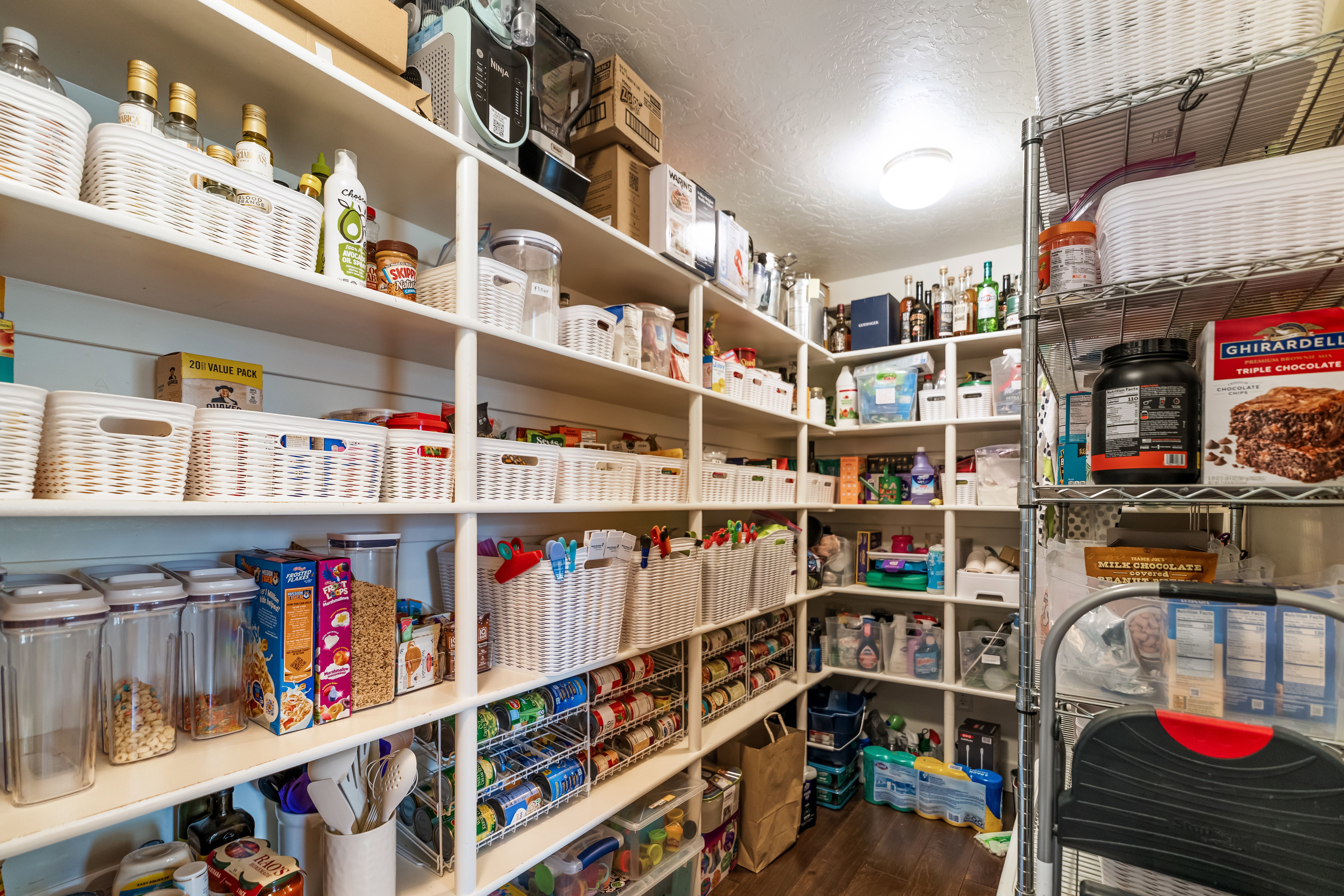 Spacious walk-in pantry featuring extensive built-in shelving, durable wood-finish flooring, and recessed ceiling lighting