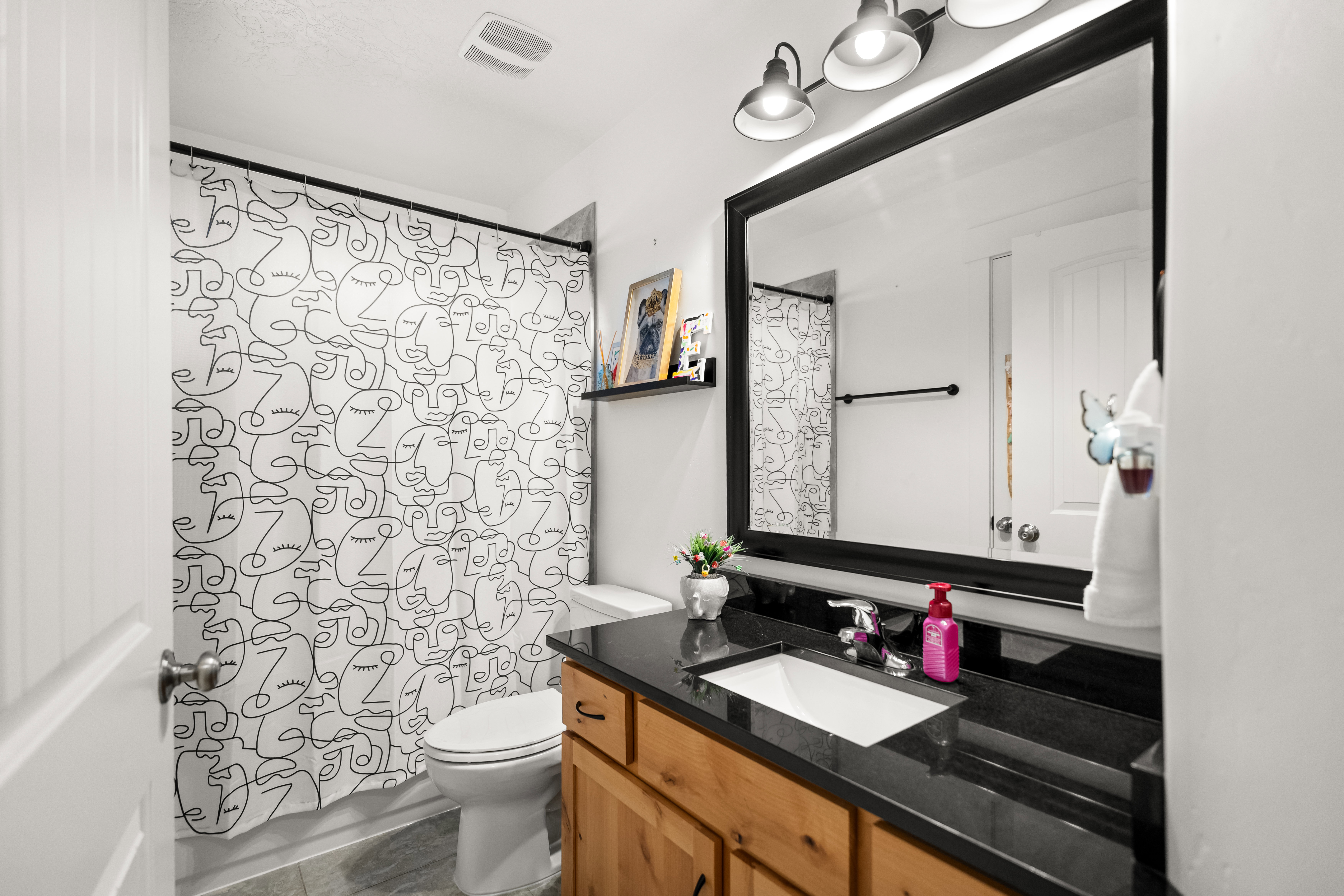 Bathroom featuring a dark wood-finish vanity with an integrated rectangular sink, a black countertop, and a large framed mirror