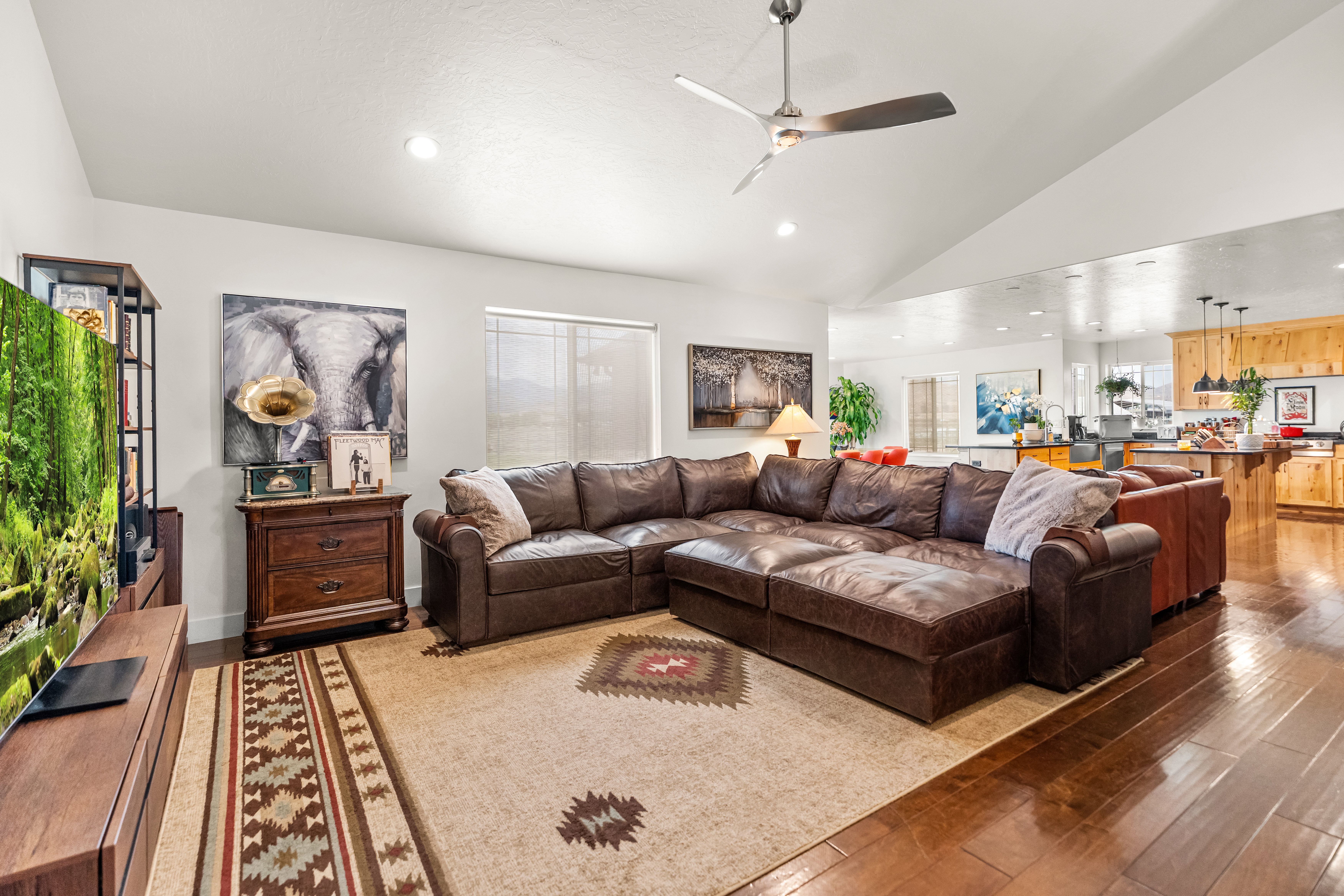 Open-concept living area featuring rich wood-finish flooring, vaulted ceilings, and recessed lighting