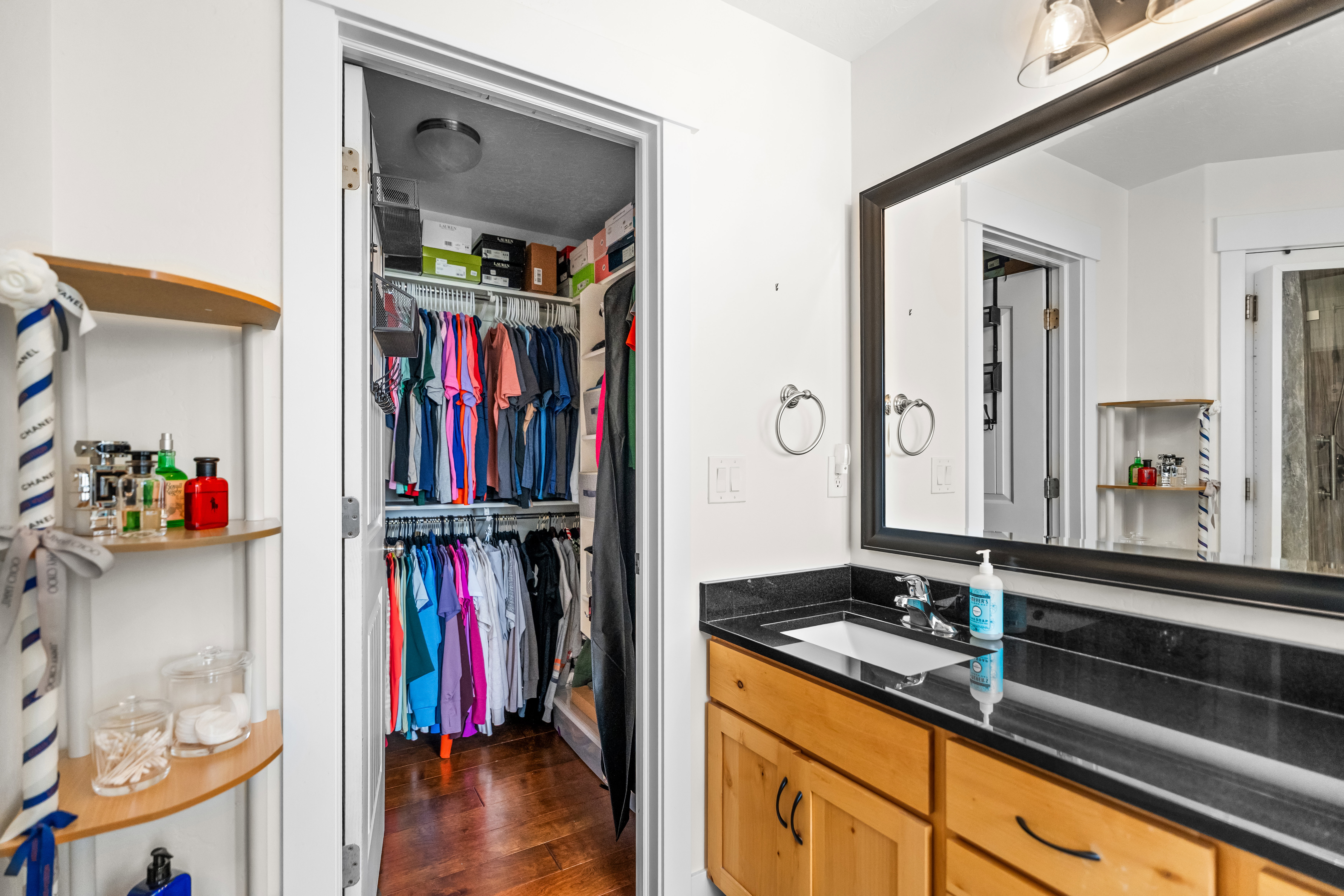 Bathroom vanity featuring light wood-finish cabinetry, a dark countertop, and a large framed mirror