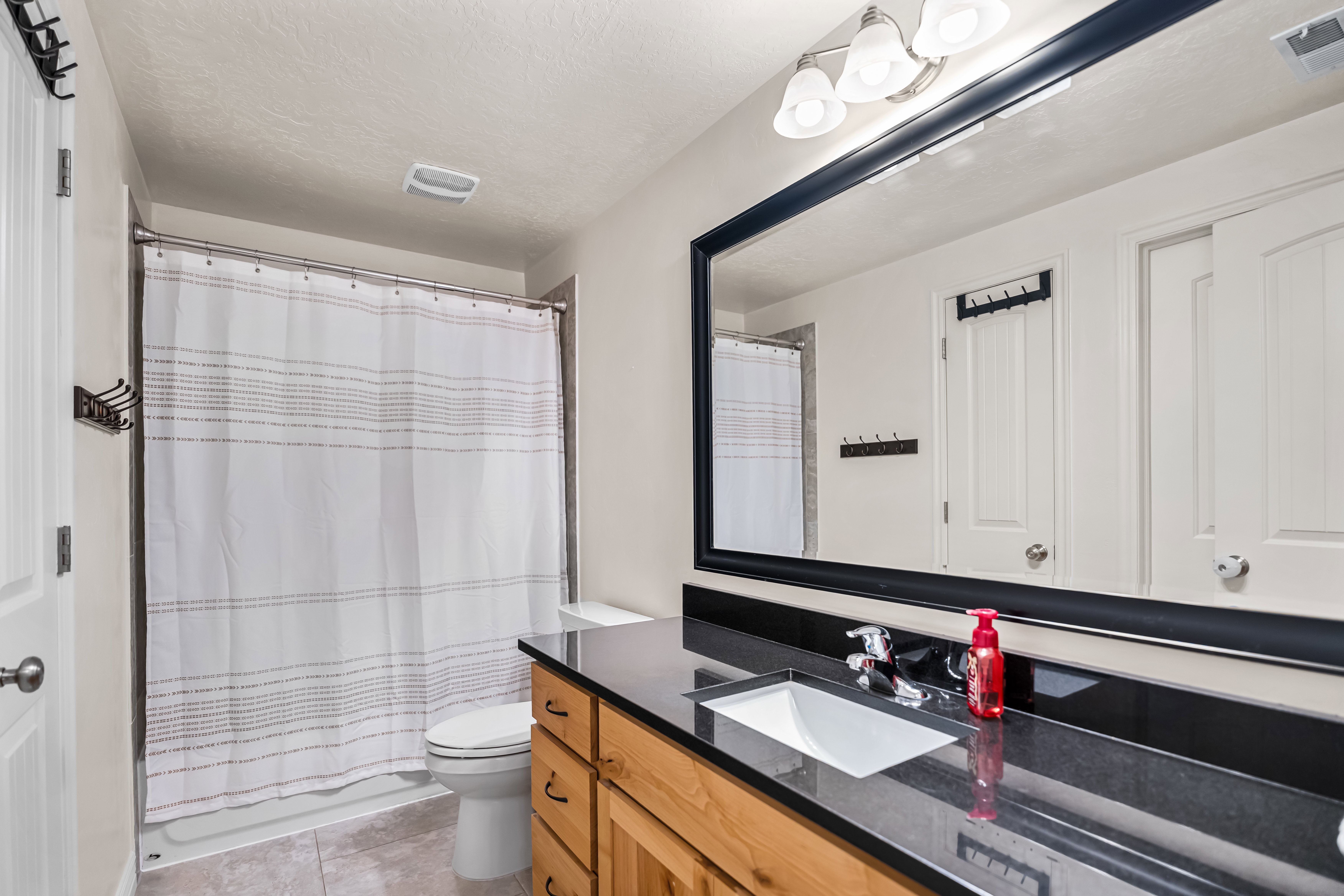 Bathroom with a long wood-finish vanity, an integrated sink, and a dark countertop