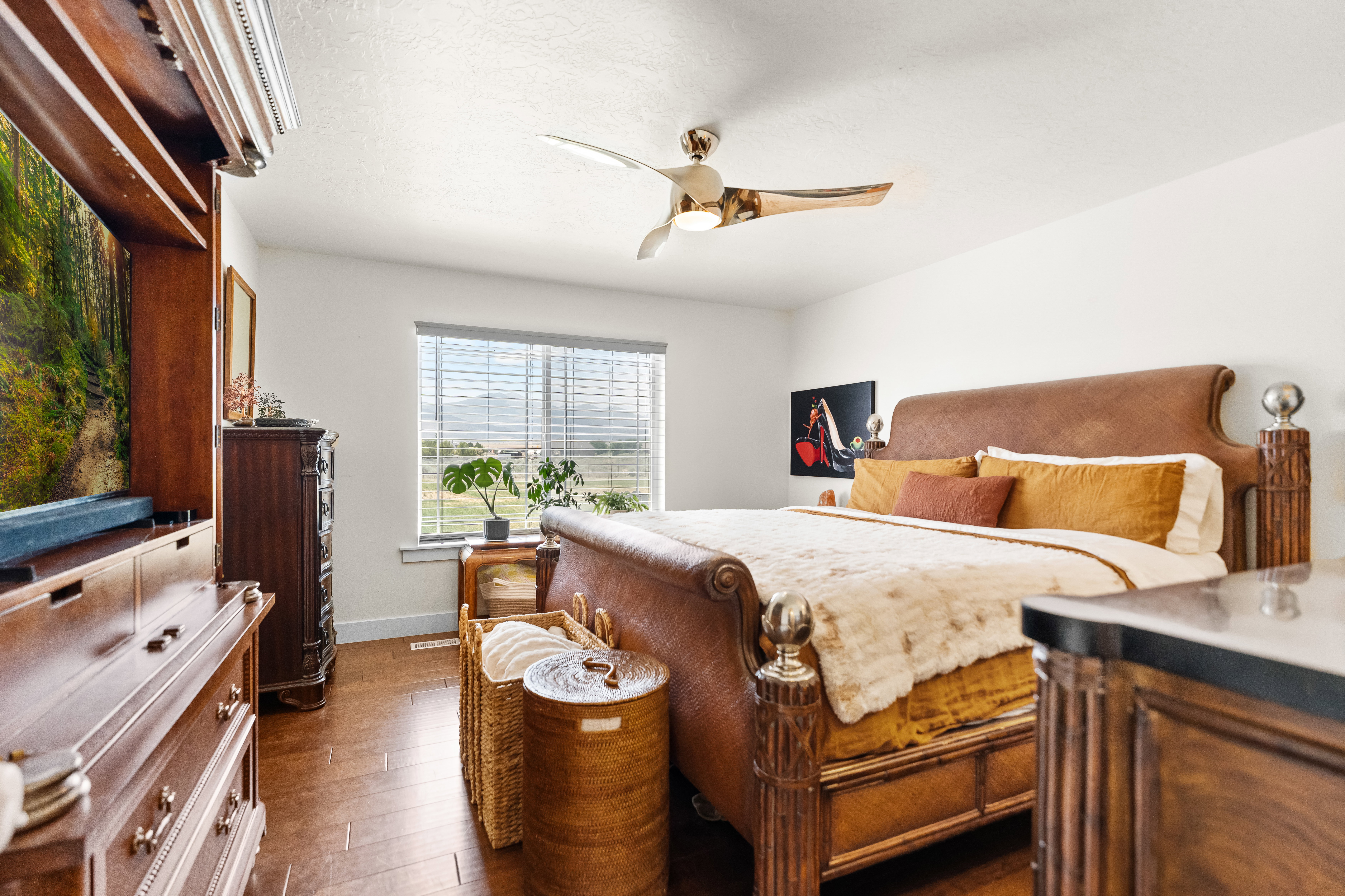 Spacious sleeping area featuring wood-finish flooring and a contemporary ceiling fan