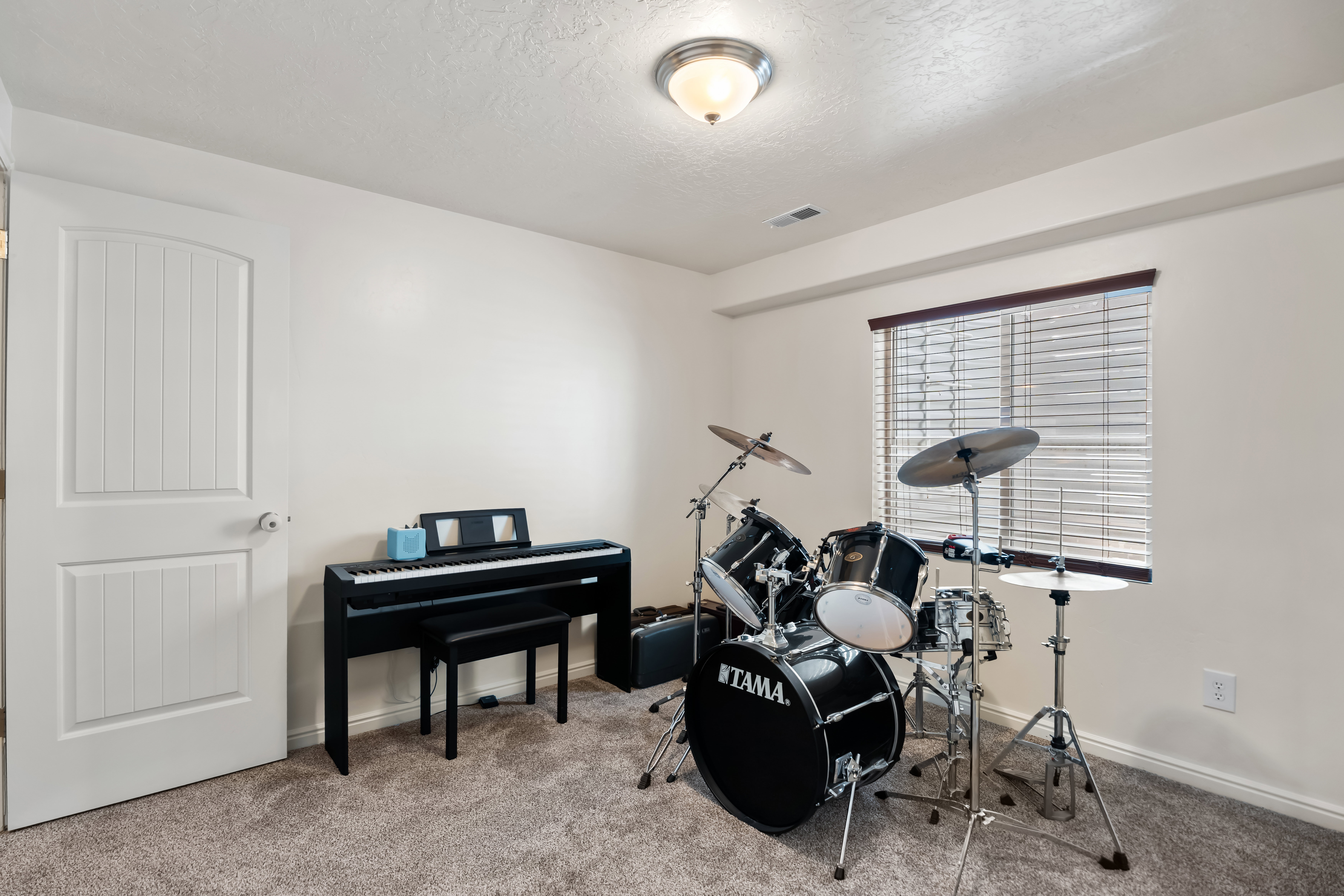 Carpeted room featuring a window with blinds, white walls, and a ceiling-mounted light fixture