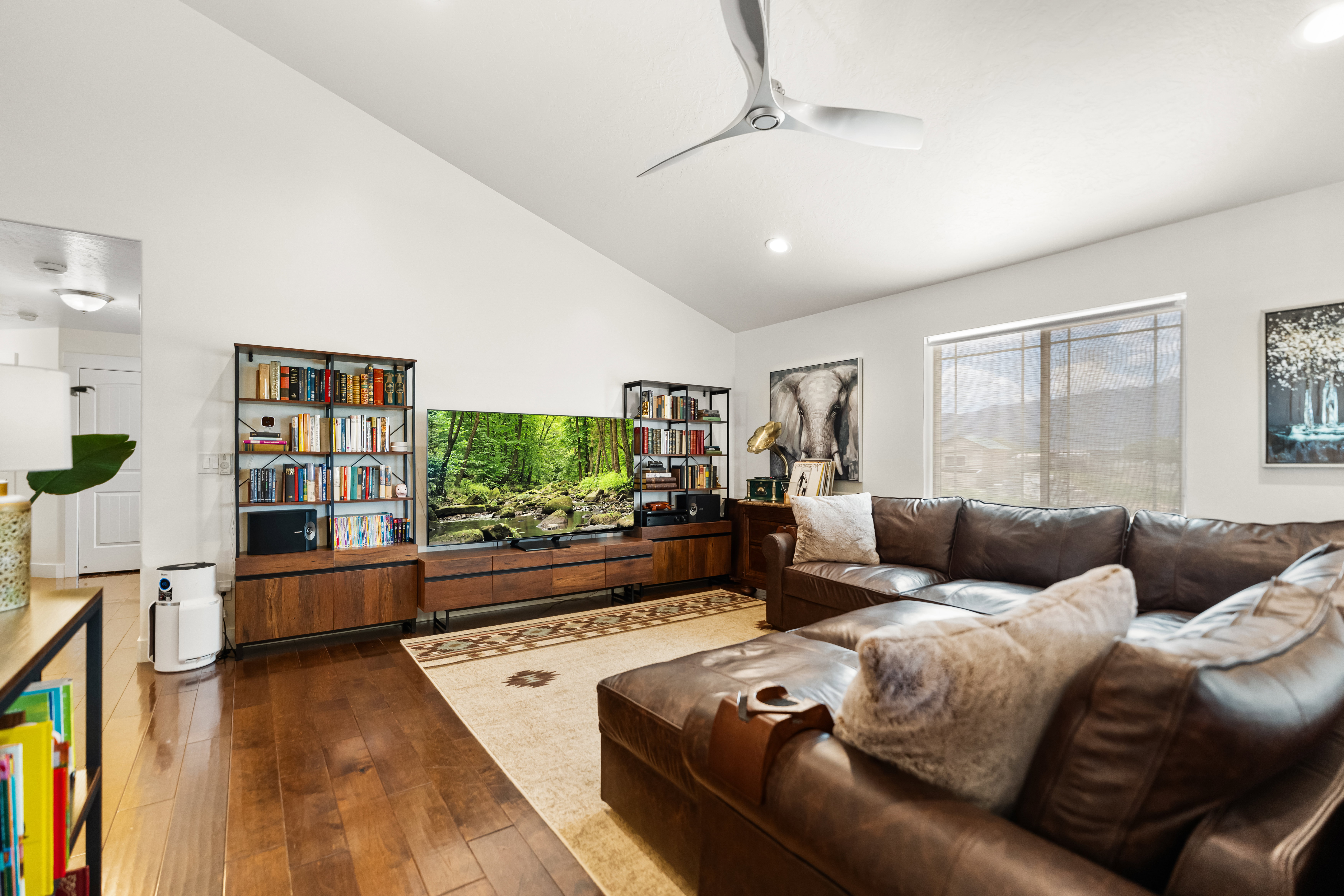Spacious living area featuring vaulted ceilings, wood-finish flooring, recessed lighting, and a large window