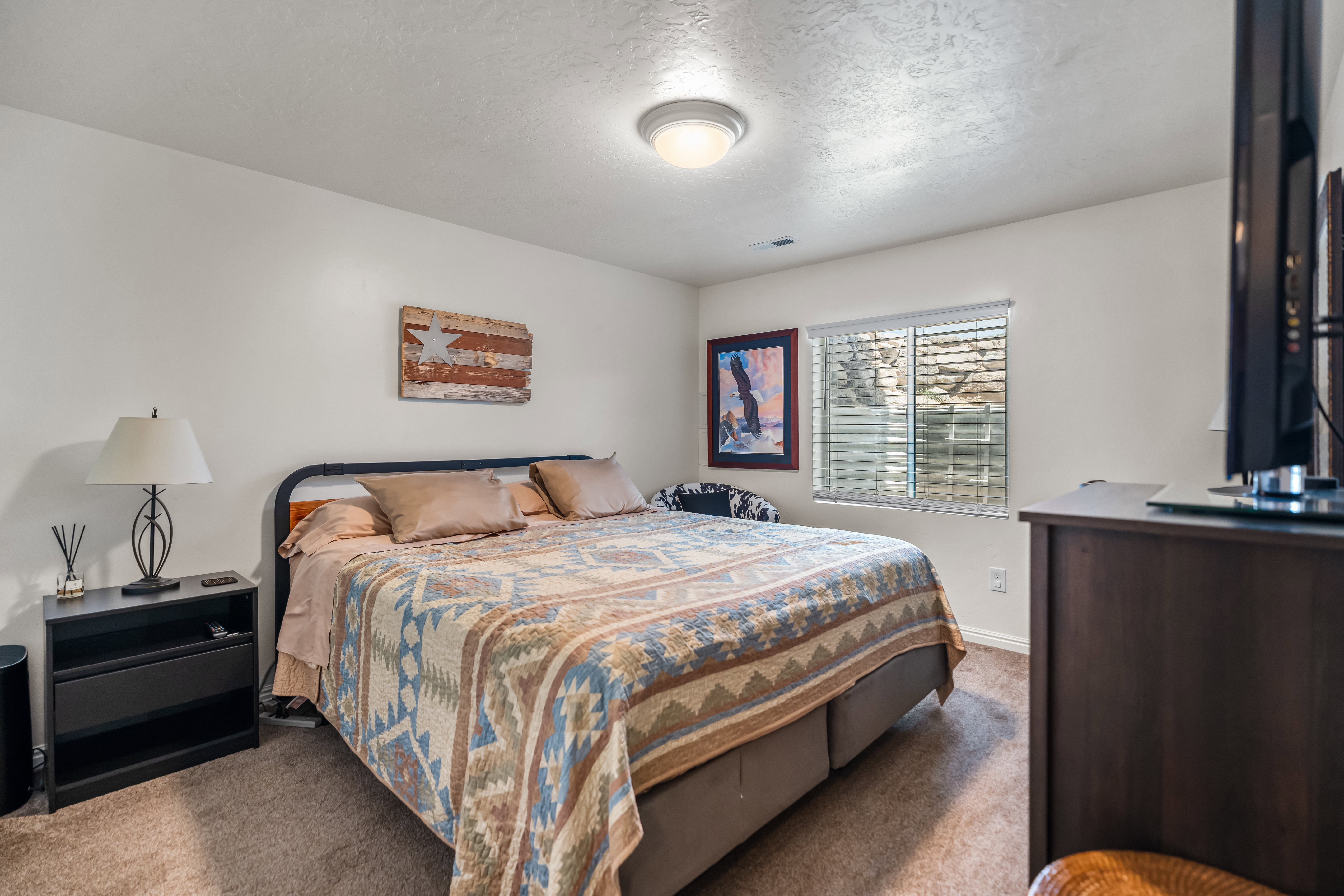 Carpeted bedroom featuring white walls and a window with blinds