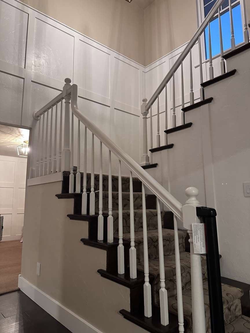 Grand staircase featuring dark wood treads with a patterned runner, white balusters, and a matching handrail