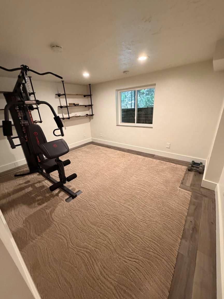 Versatile room featuring a window, recessed lighting, and a combination of patterned carpet and wood-finish flooring