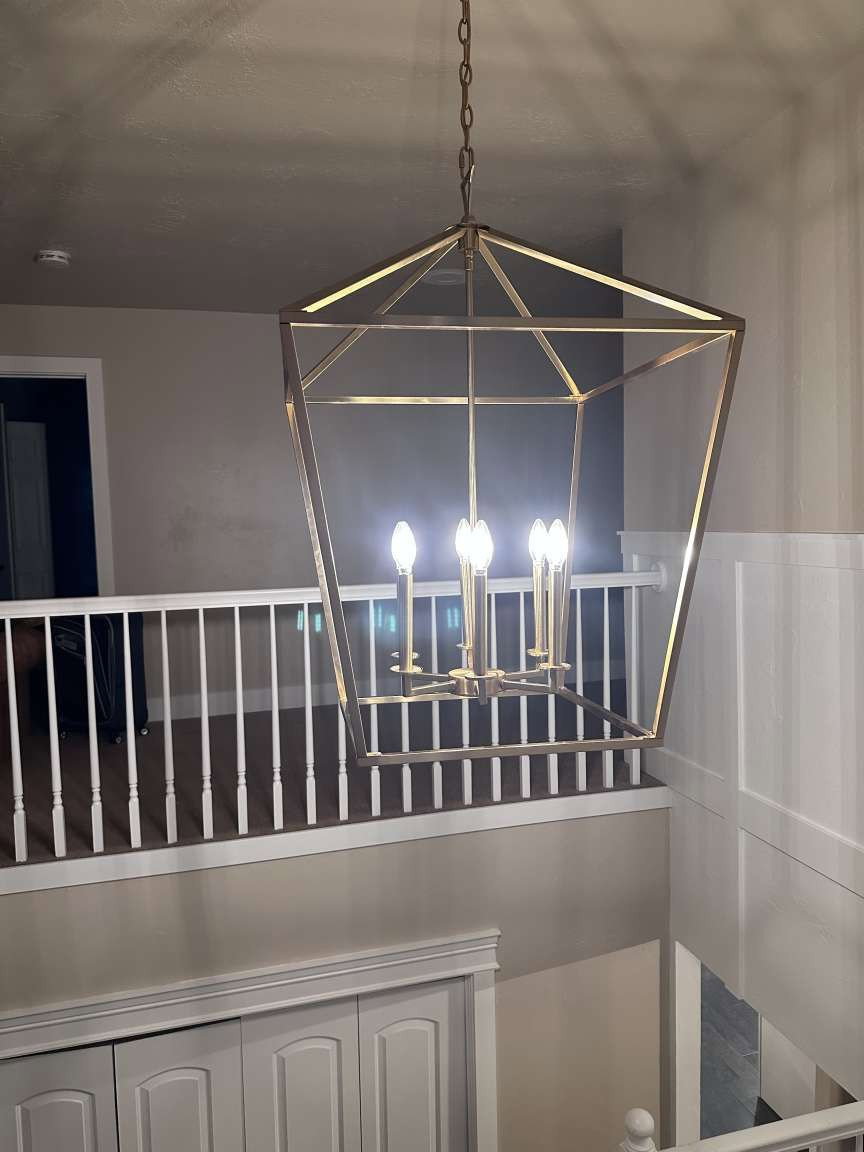 Geometric chandelier with a metallic finish, illuminating the two-story entry