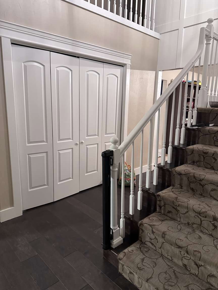 Dark wood-finish flooring complements the detailed carpeted staircase with white balusters