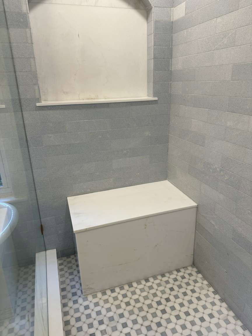 Shower stall featuring light gray subway tile walls and a decorative mosaic tile floor