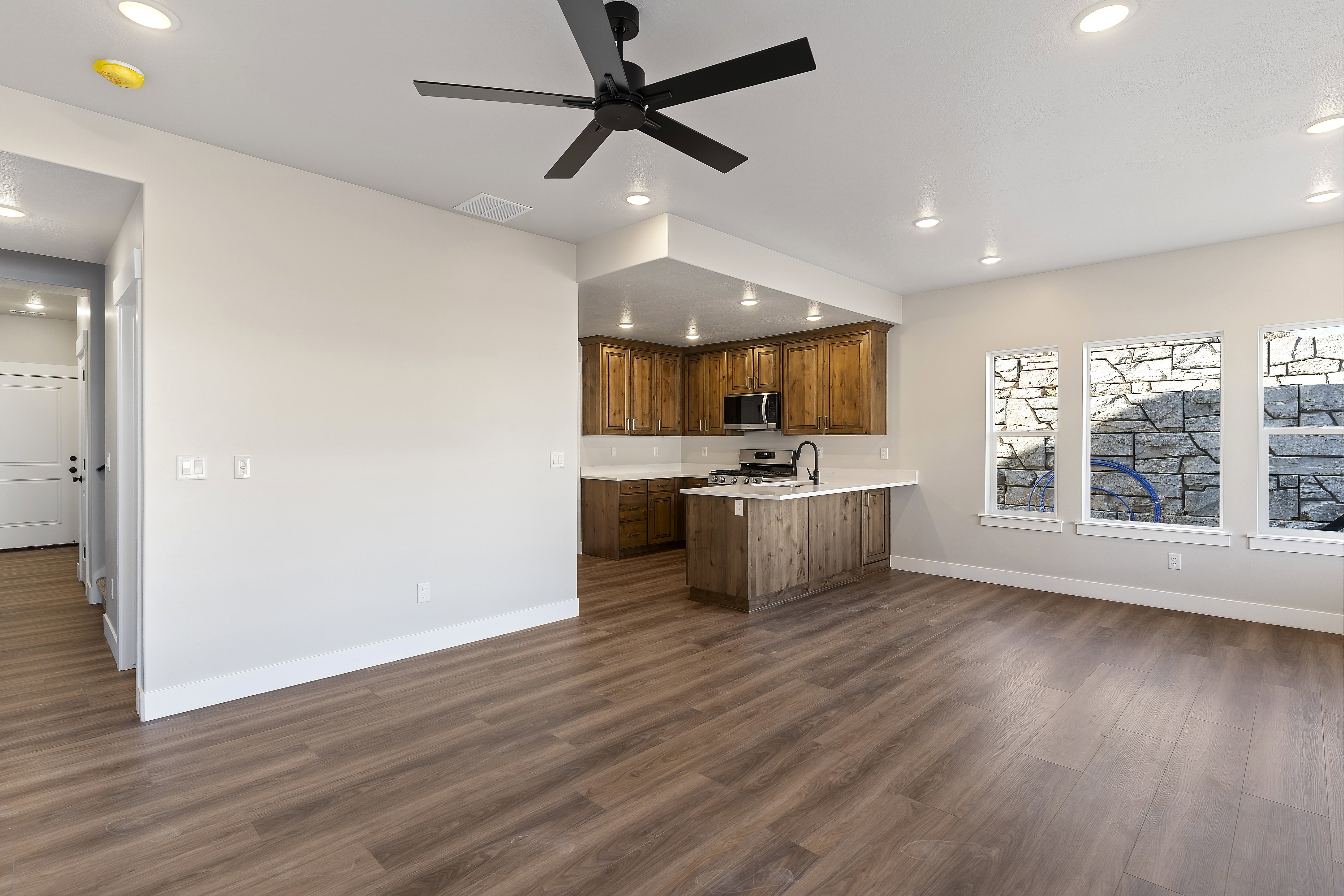 Open-concept living area with wood-finish flooring, recessed lighting, and a ceiling fan