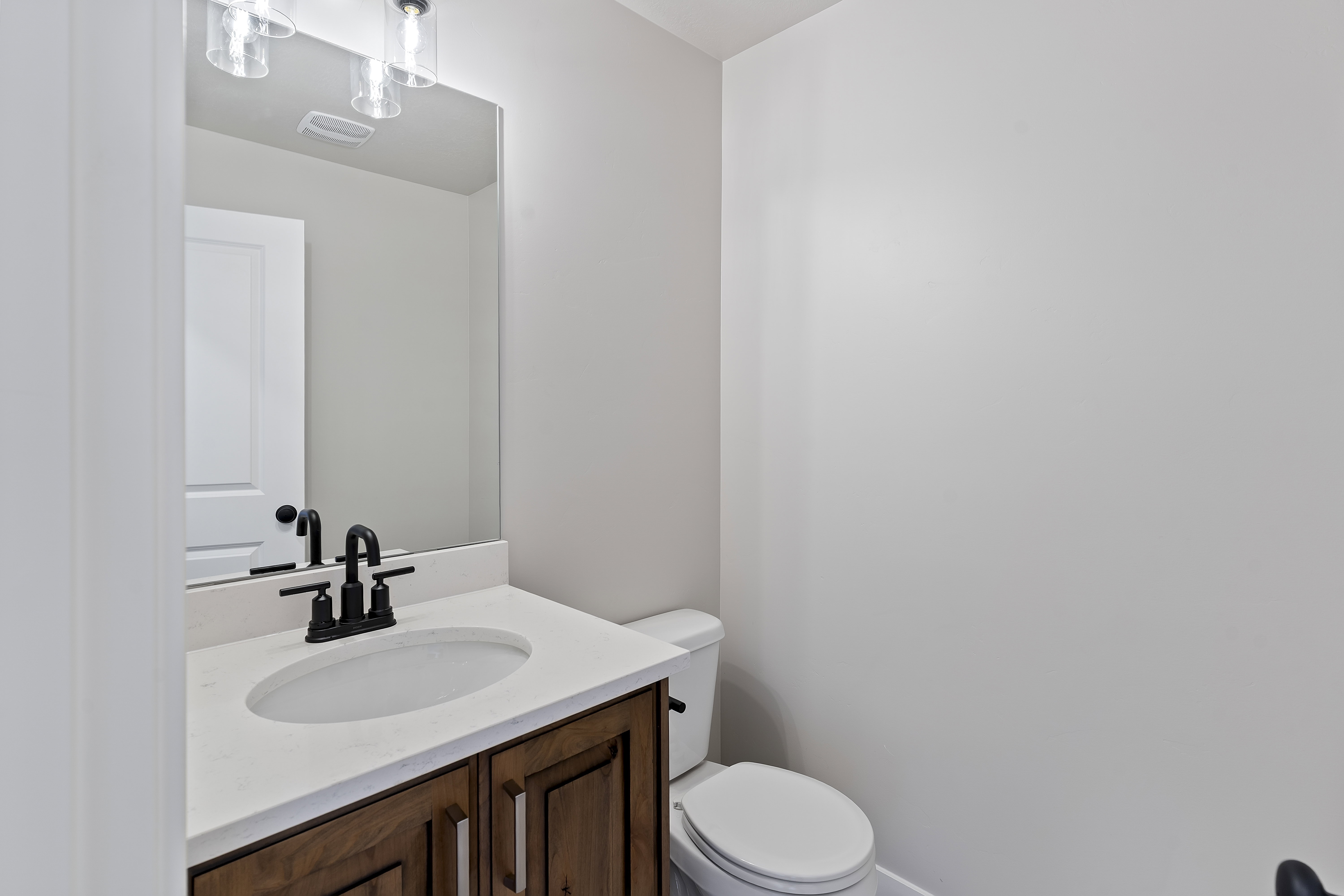 Bathroom featuring a dark wood vanity with a white countertop, undermount sink, and matte black faucet