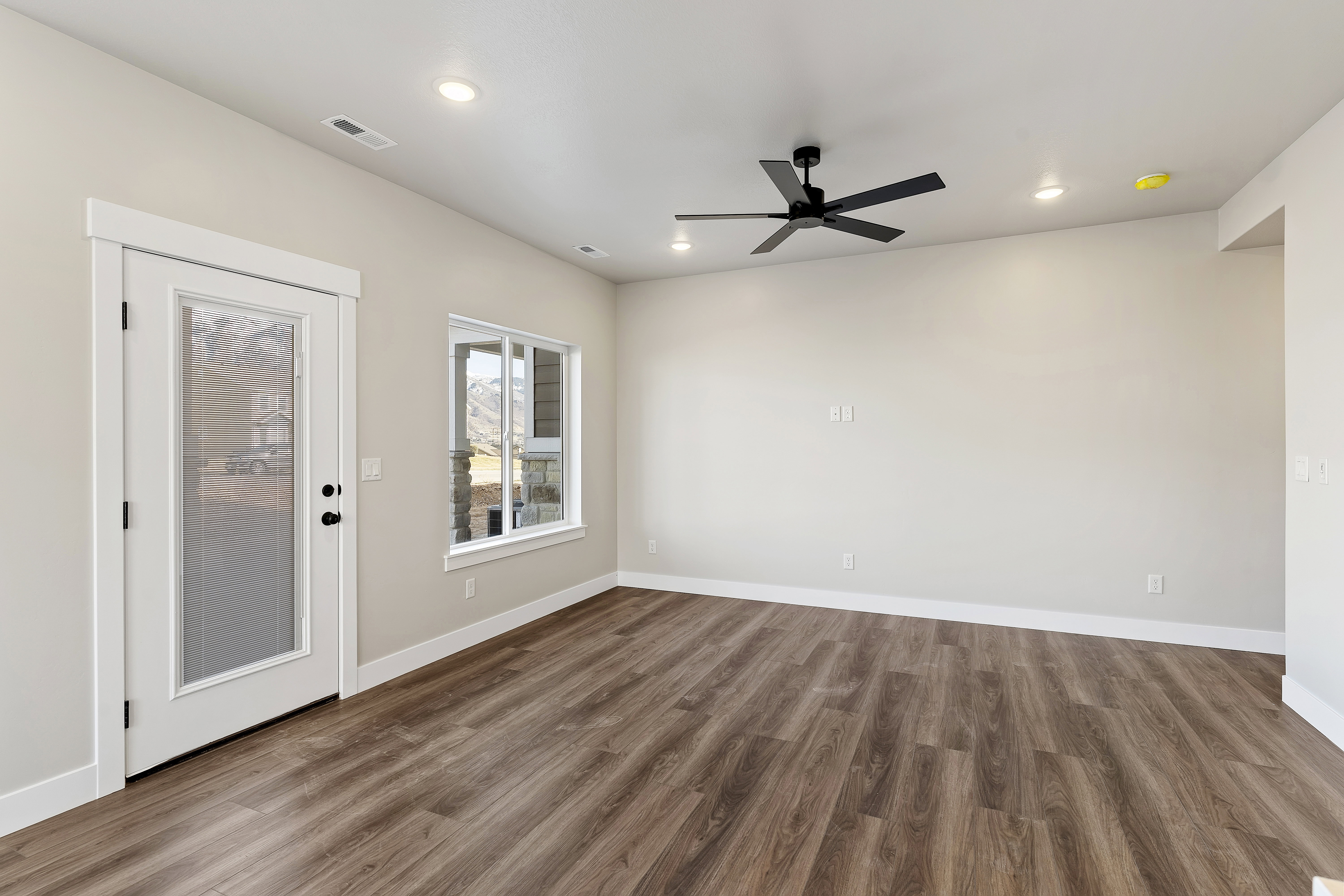 Spacious room featuring wood-finish flooring, recessed lighting, and a contemporary black ceiling fan