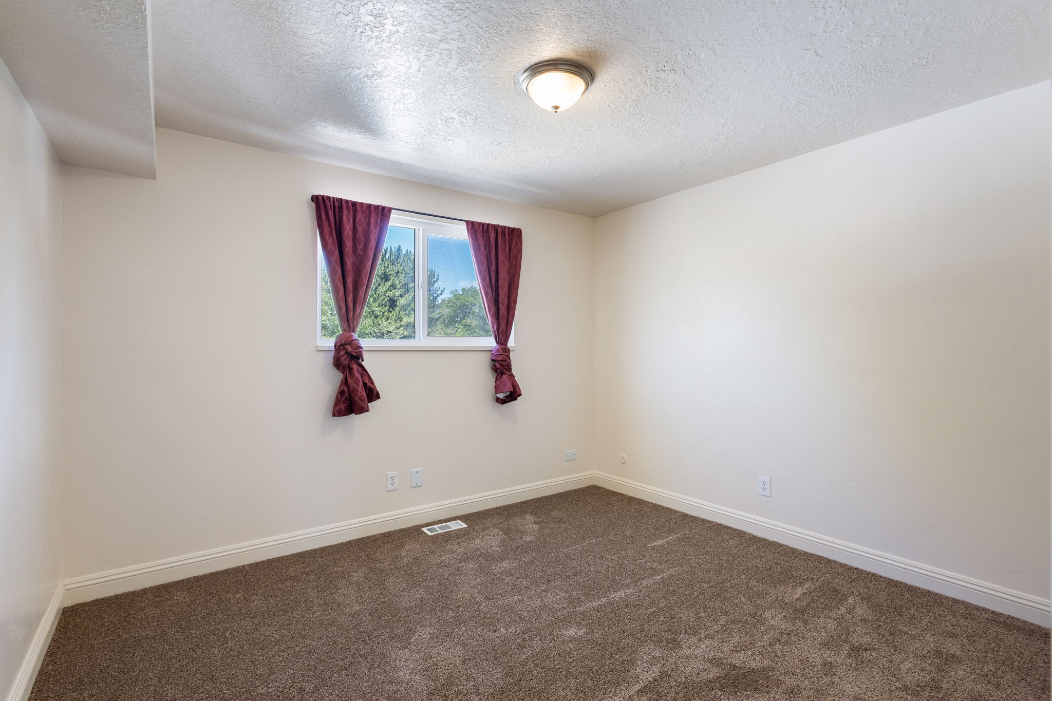 Neutral wall tones with a window, baseboard trim, and a ceiling-mounted light fixture