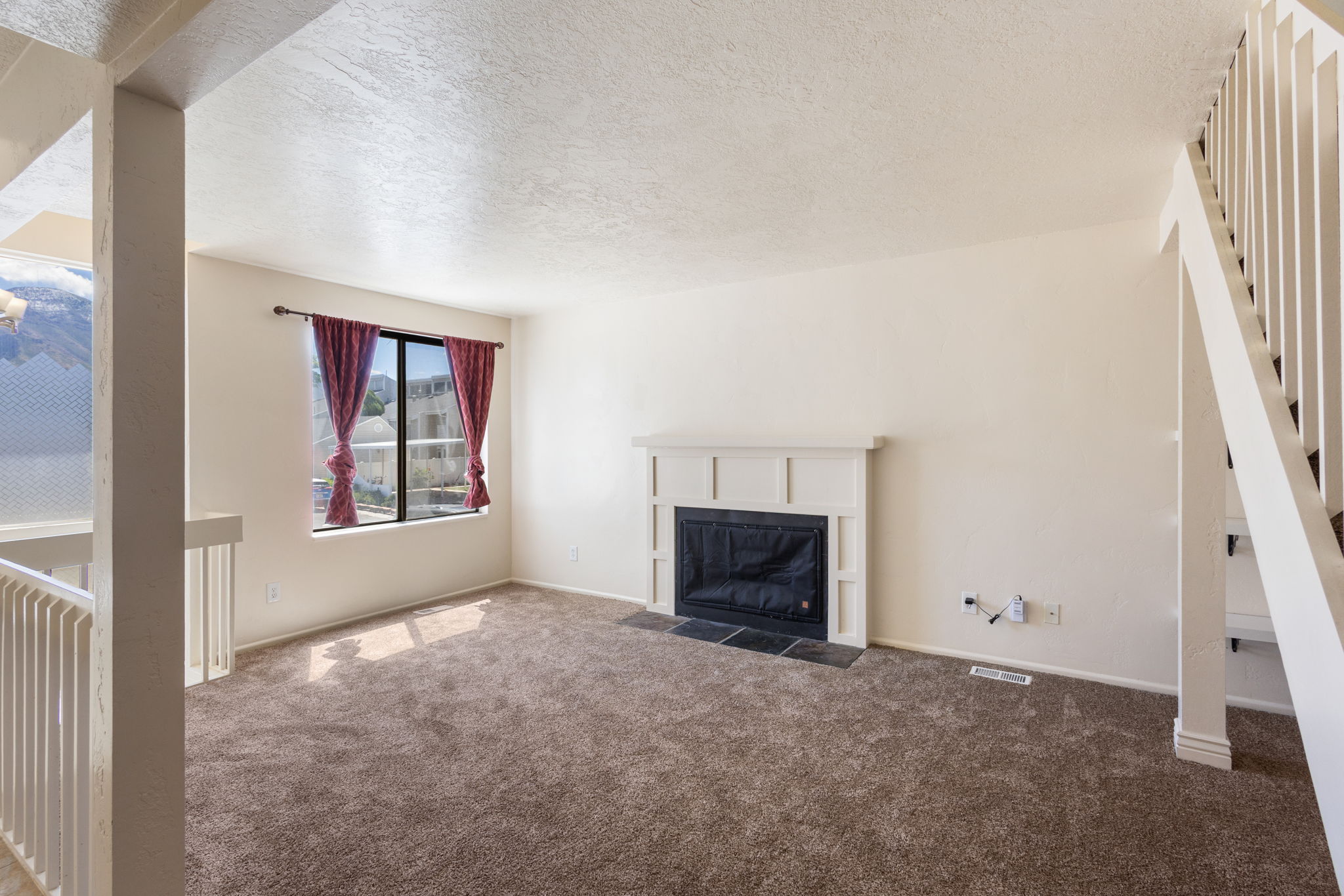 Living space with carpeting, a white mantel fireplace featuring a dark tile hearth, and a large window