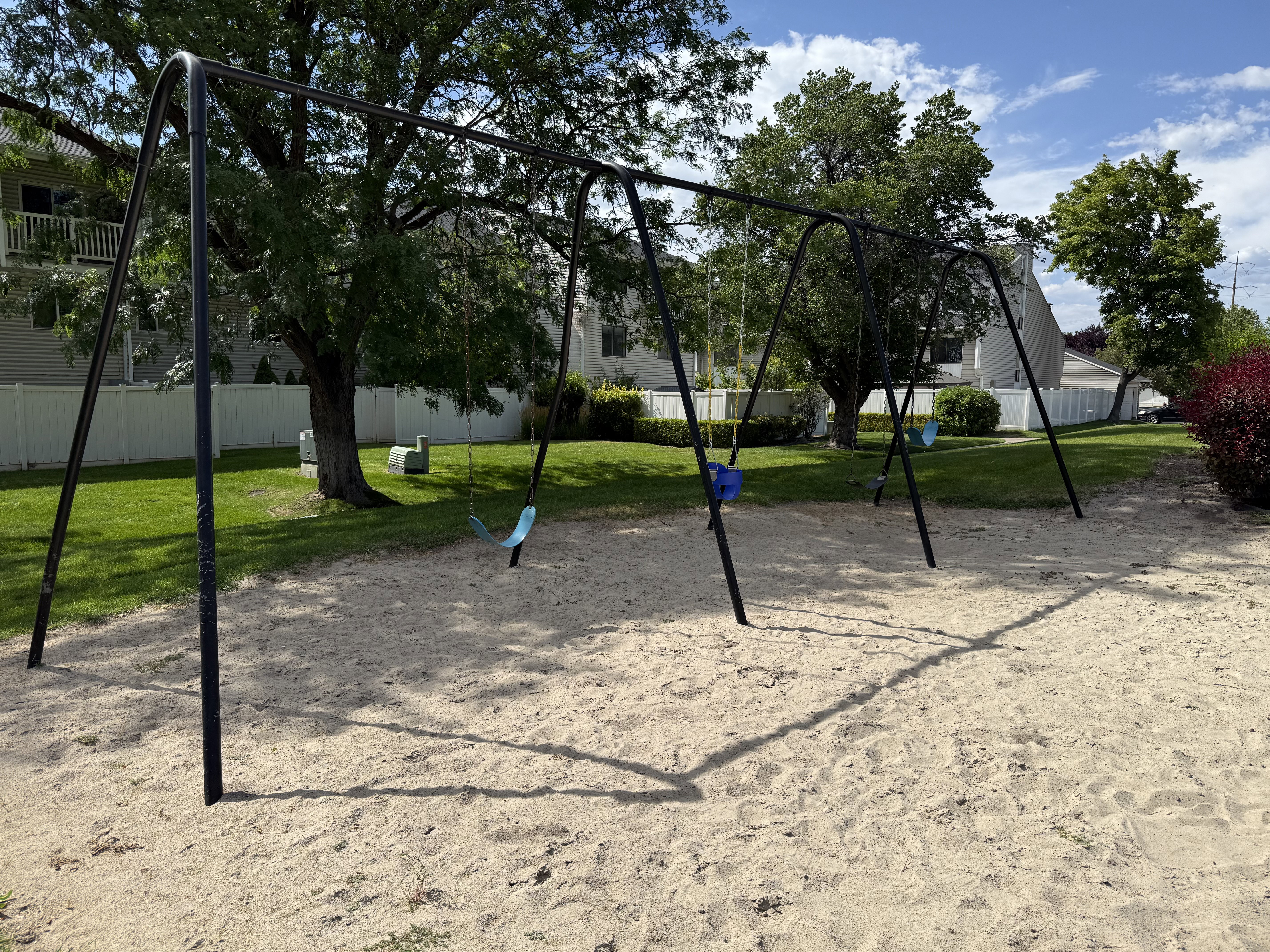 Outdoor recreational area featuring a sand base and a multi-swing set with three swings