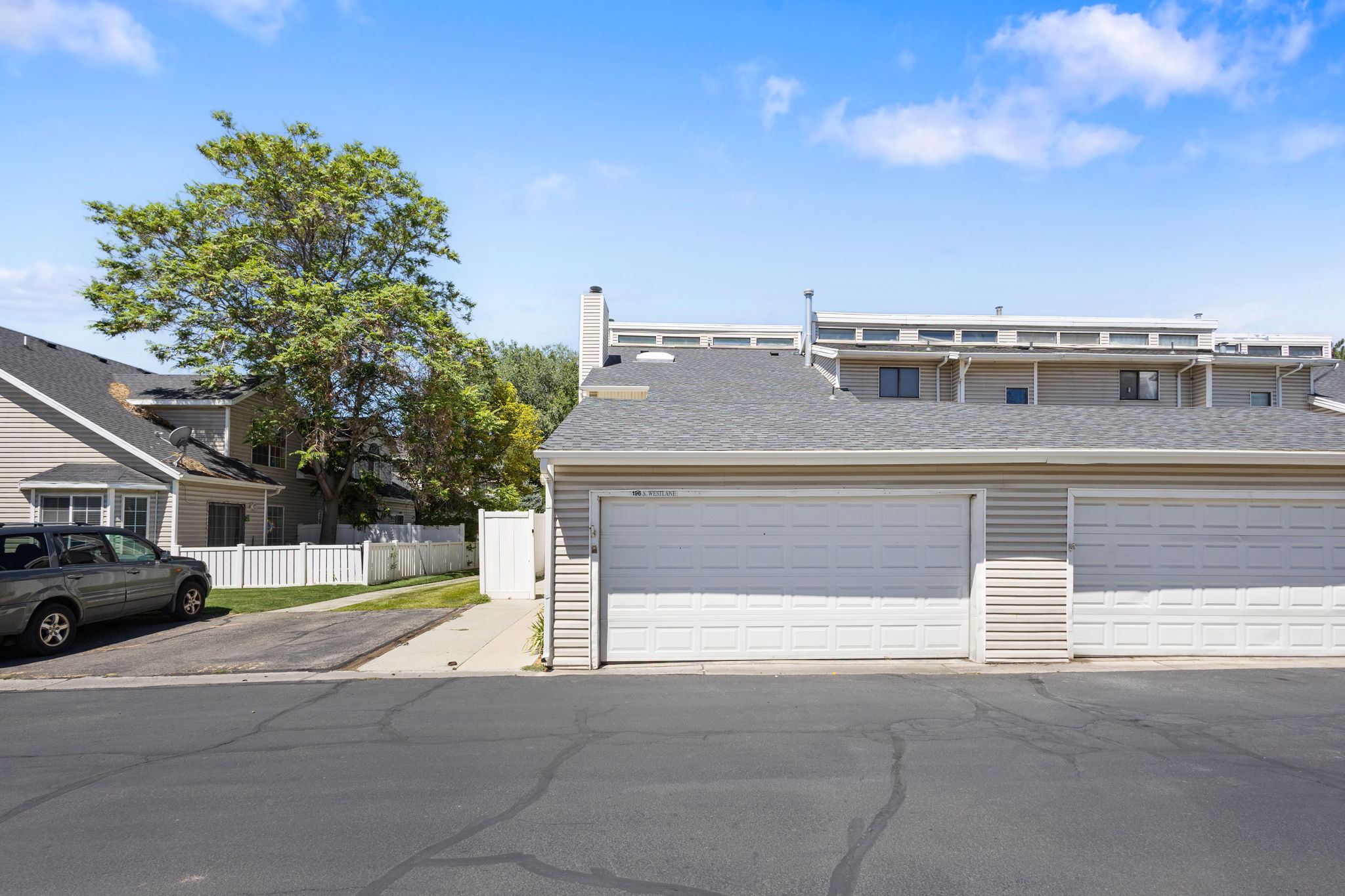 Attached two-car garage with white paneled doors and light-colored siding