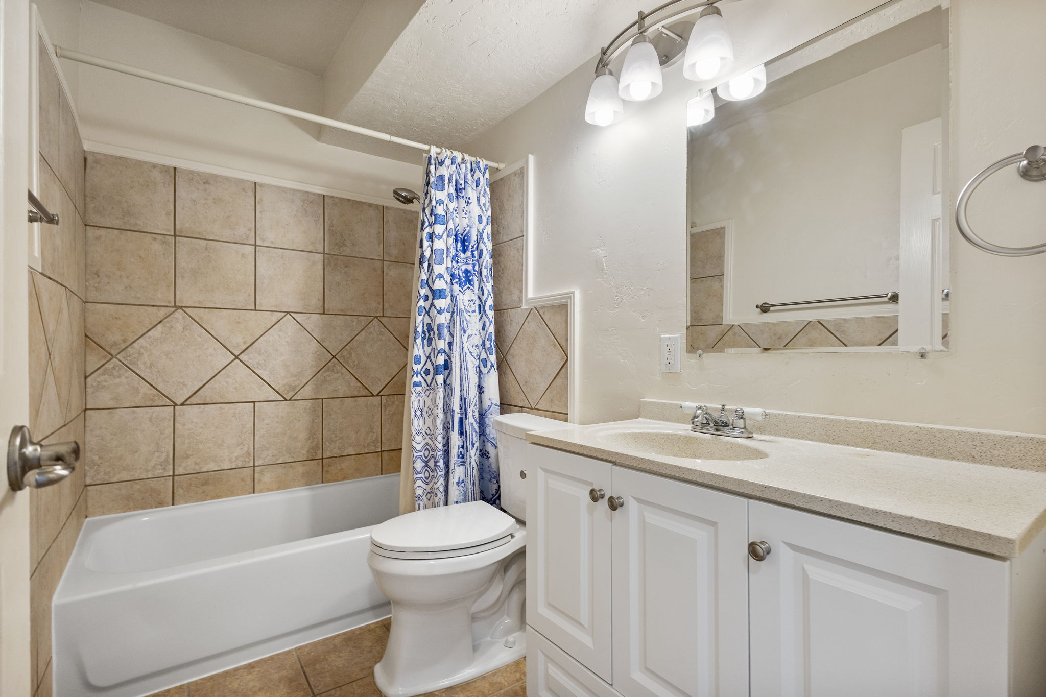 Bathroom featuring a white vanity with cabinet storage, a light-toned countertop, and an integrated sink with a chrome faucet