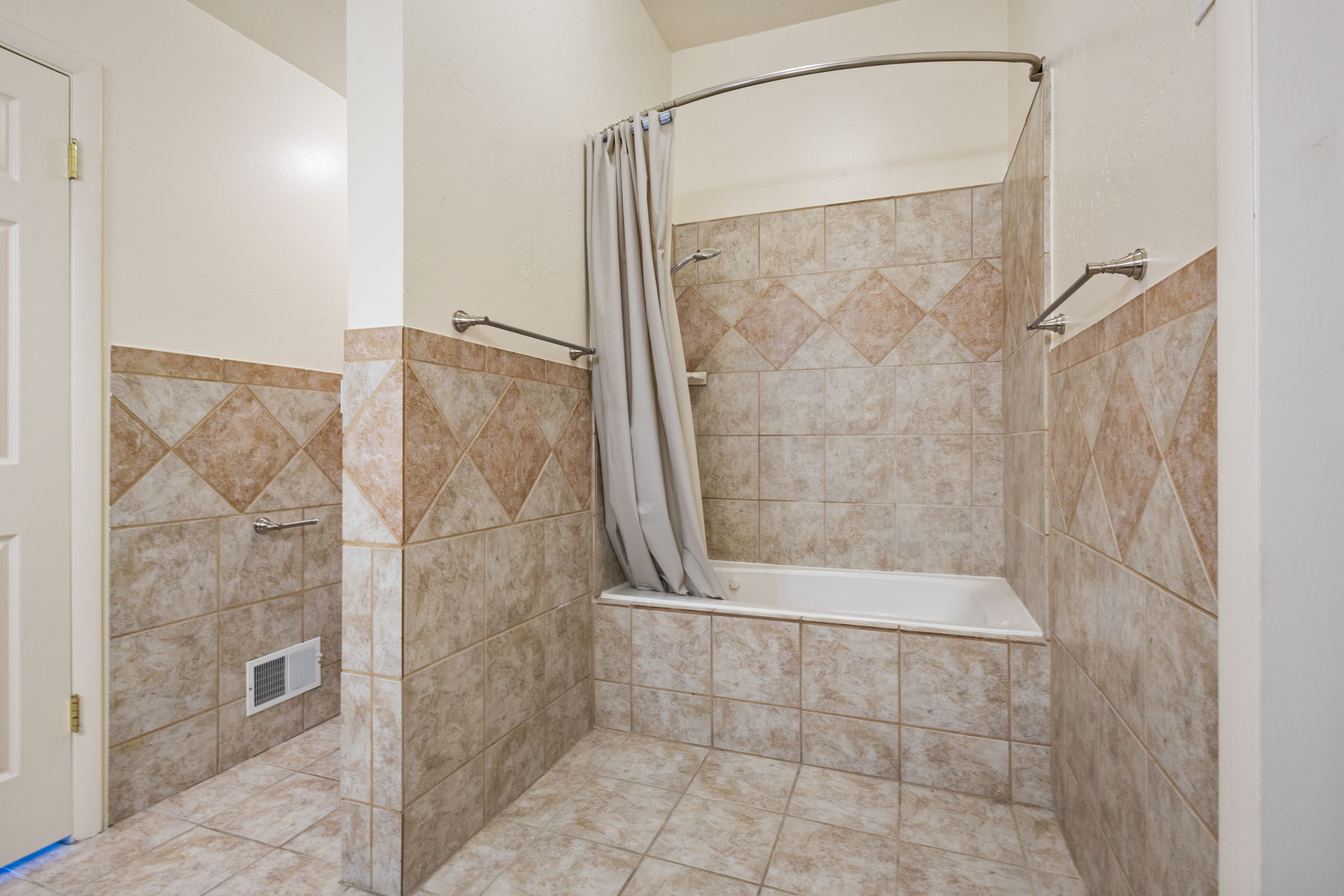 Bathroom featuring a white bathtub, ceramic tile surround with decorative accents, and coordinating floor tile