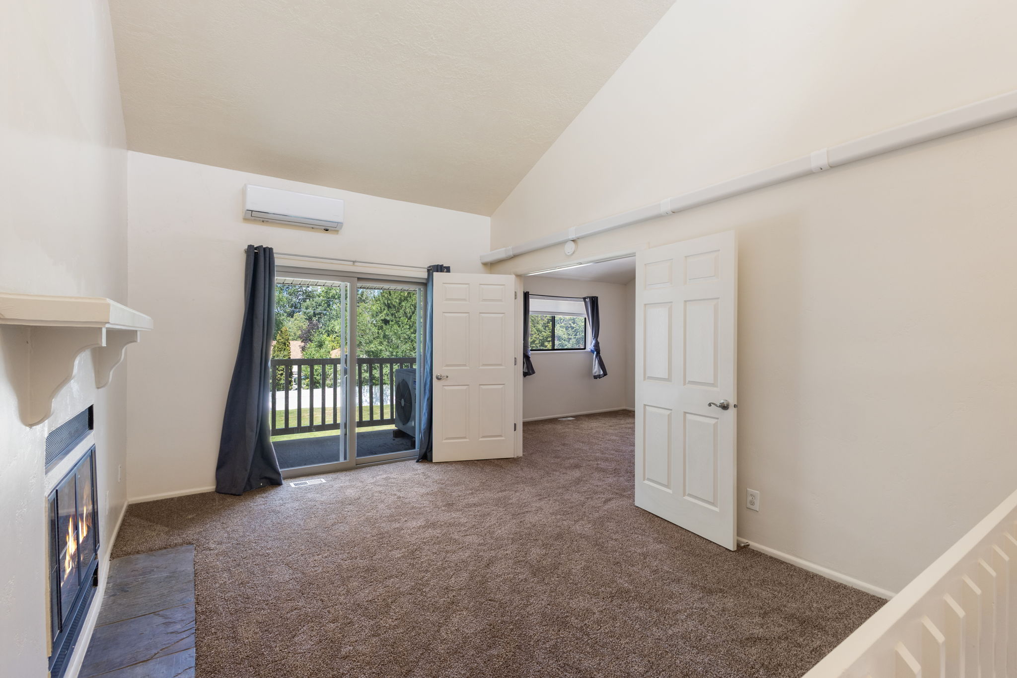 Living area featuring a vaulted ceiling and a built-in fireplace with a stone hearth