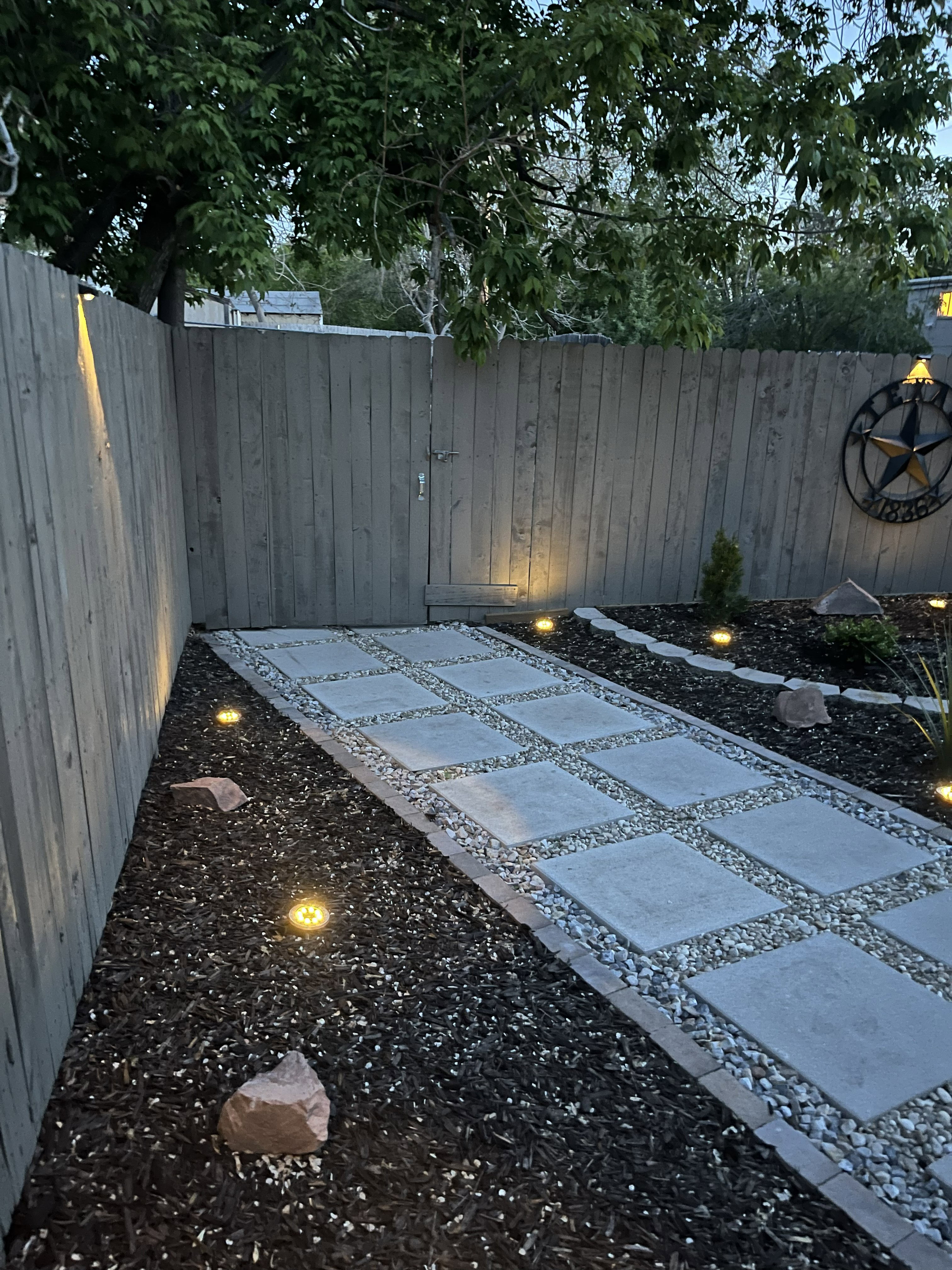 Xeriscaped backyard with pavers and accent lighting.