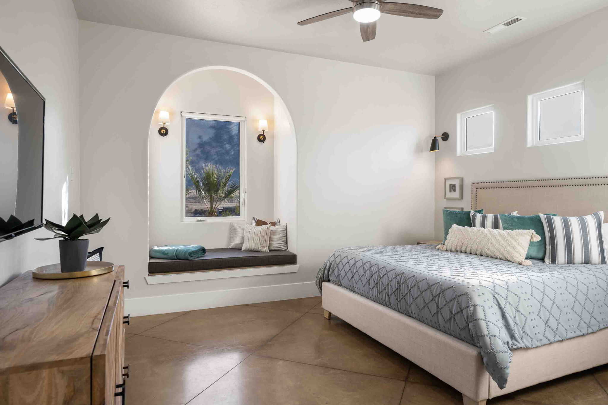 Arched window nook with built-in bench seating and twin sconce lighting