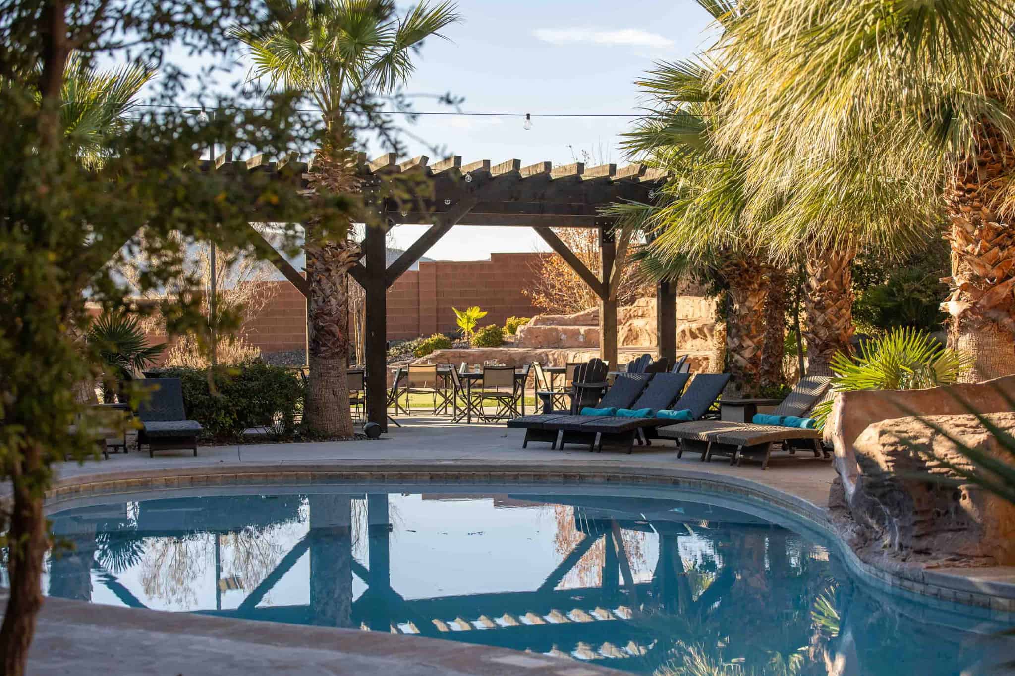 Curved swimming pool with a stone water feature, framed by mature palm trees