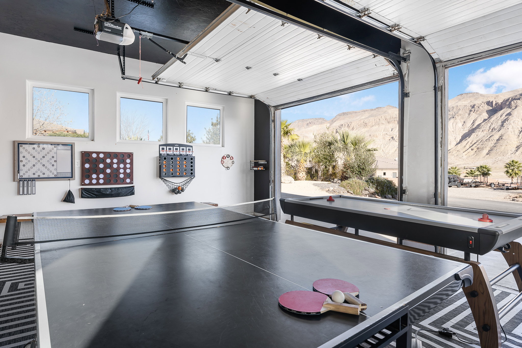 Open-concept recreation area featuring a full-size ping-pong table and a retractable garage door opening to mountain scenery