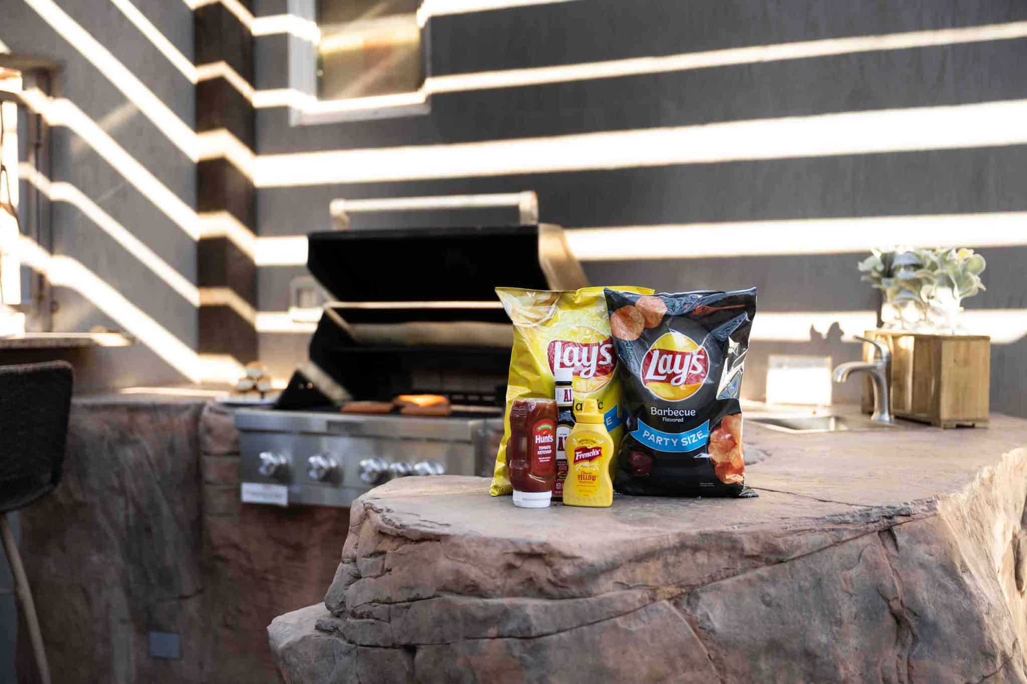 Outdoor kitchen featuring a built-in stainless steel grill, stone countertops, and an integrated sink with a stainless steel faucet