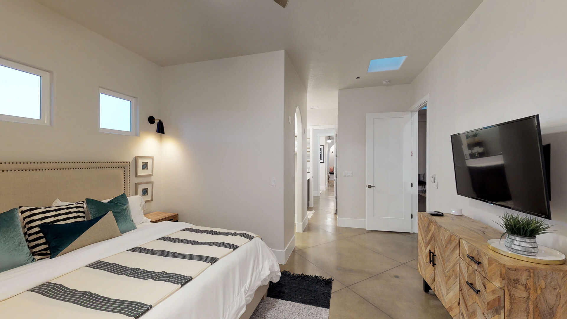 Bedroom featuring multiple windows for illumination, a skylight, and concrete flooring