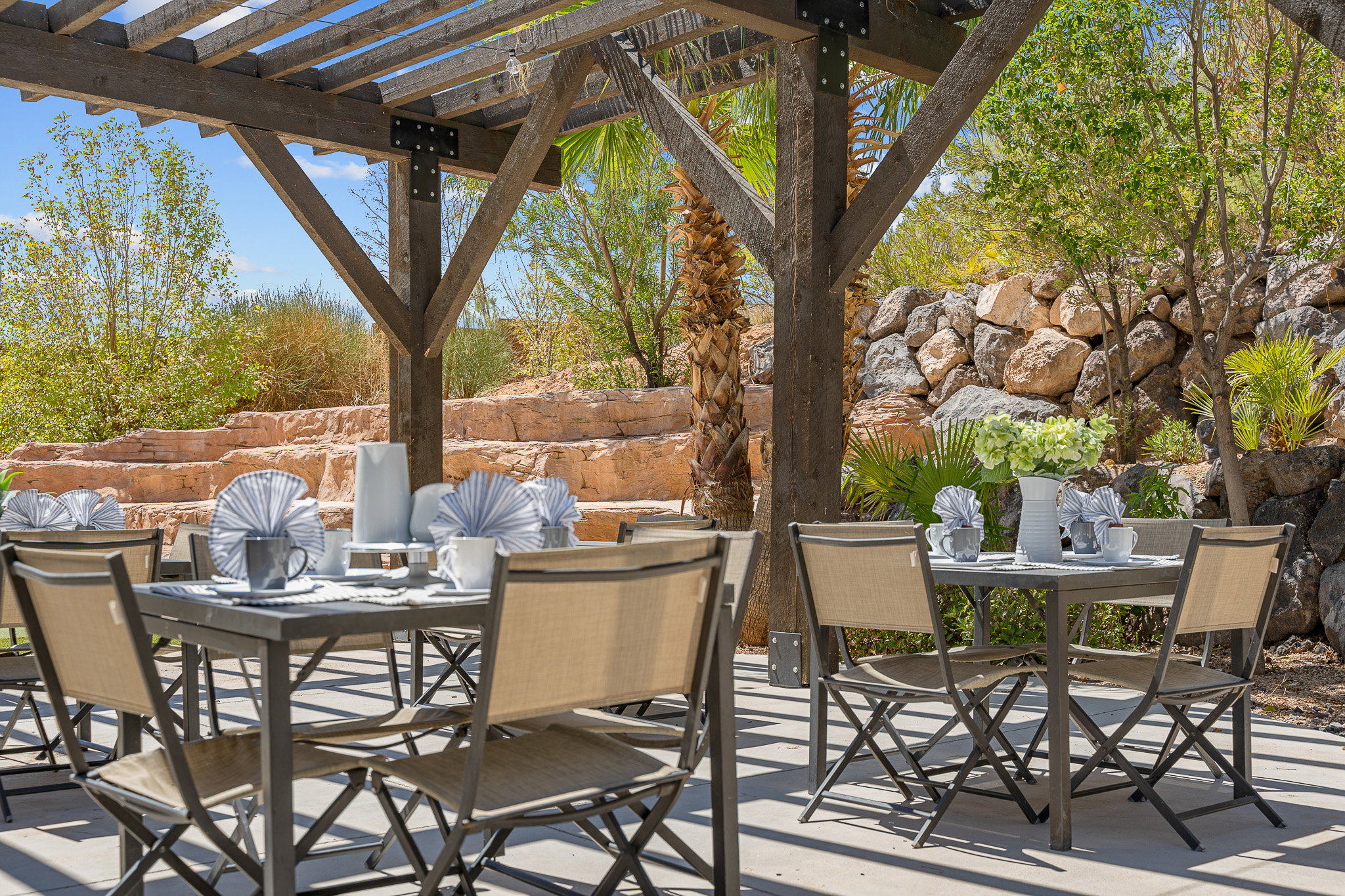 Outdoor dining area featuring a wooden pergola with substantial beams
