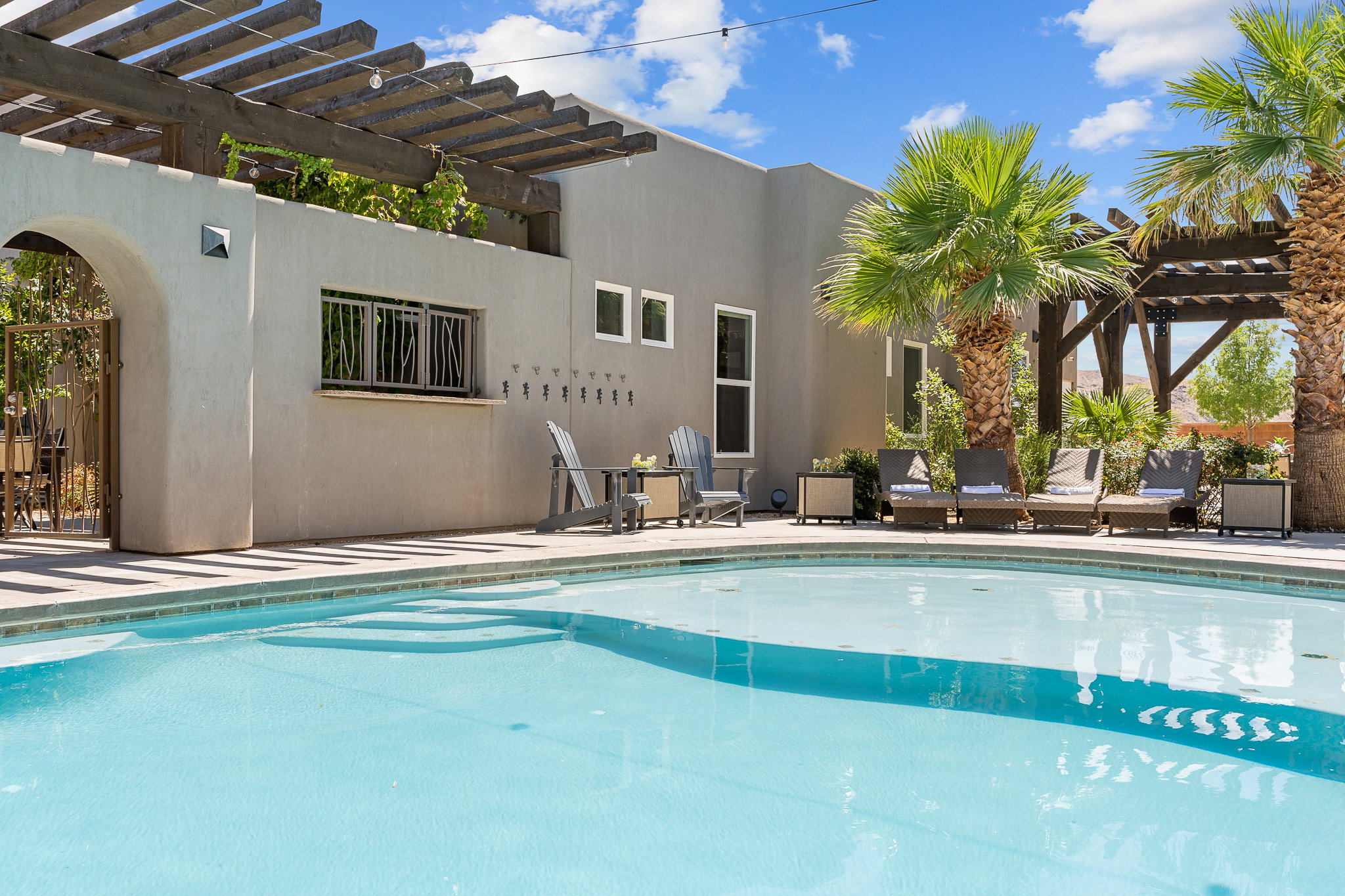 Freeform swimming pool with integrated steps, surrounded by a light-colored paved patio