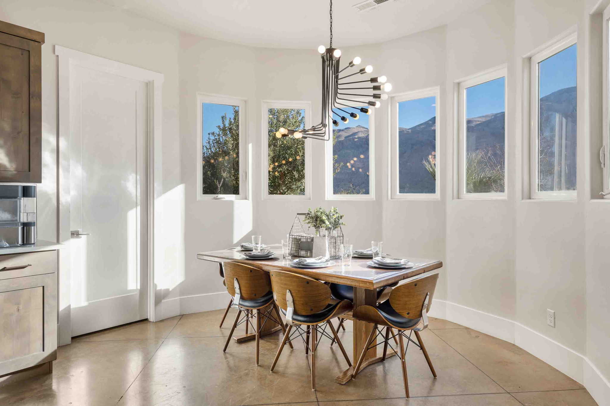 Dining area featuring a modern chandelier, a curved wall with multiple windows, concrete-finish flooring, and built-in cabinetry