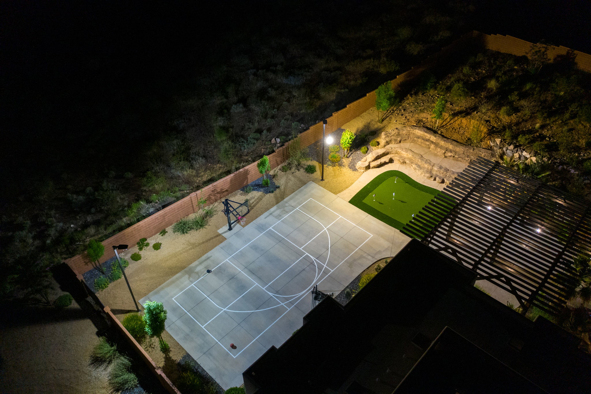 Outdoor sports court with painted lines, integrated basketball hoop, and adjacent putting green