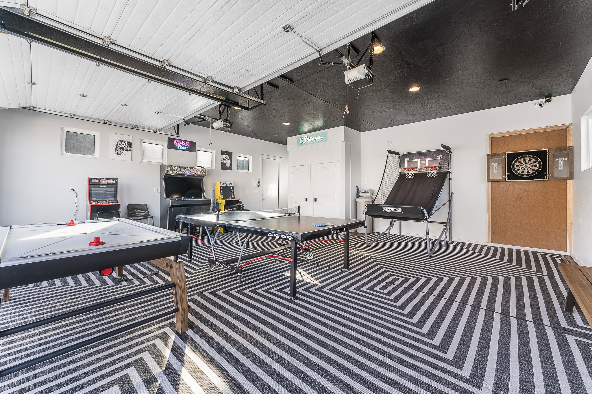 Versatile bonus room featuring a black and white geometric patterned floor, a white paneled overhead garage door, and a contrasting black ceiling with recessed lighting