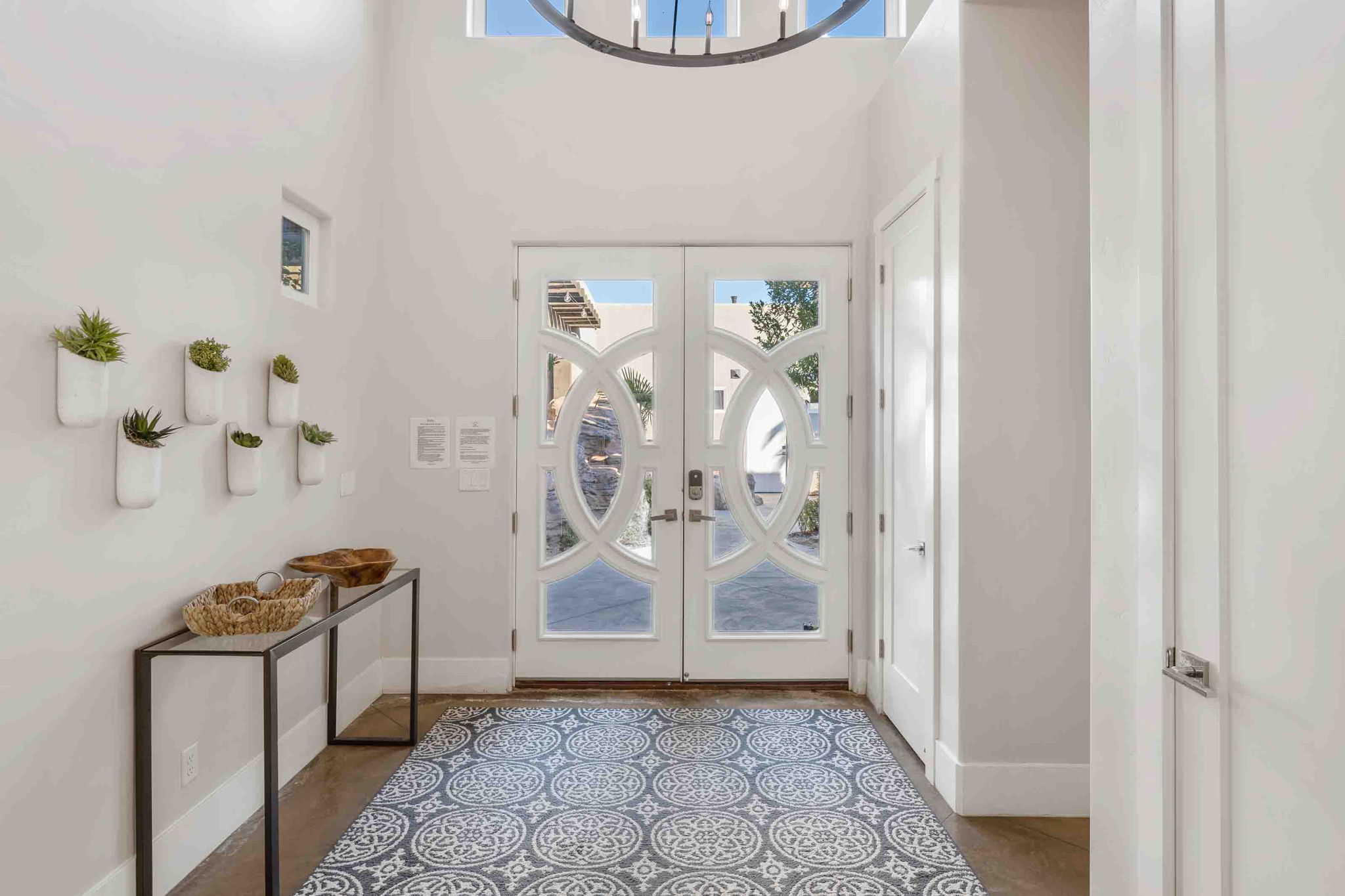 Entryway featuring double glass-panel doors with decorative mullions, a patterned floor covering, and a high ceiling with an overhead light fixture