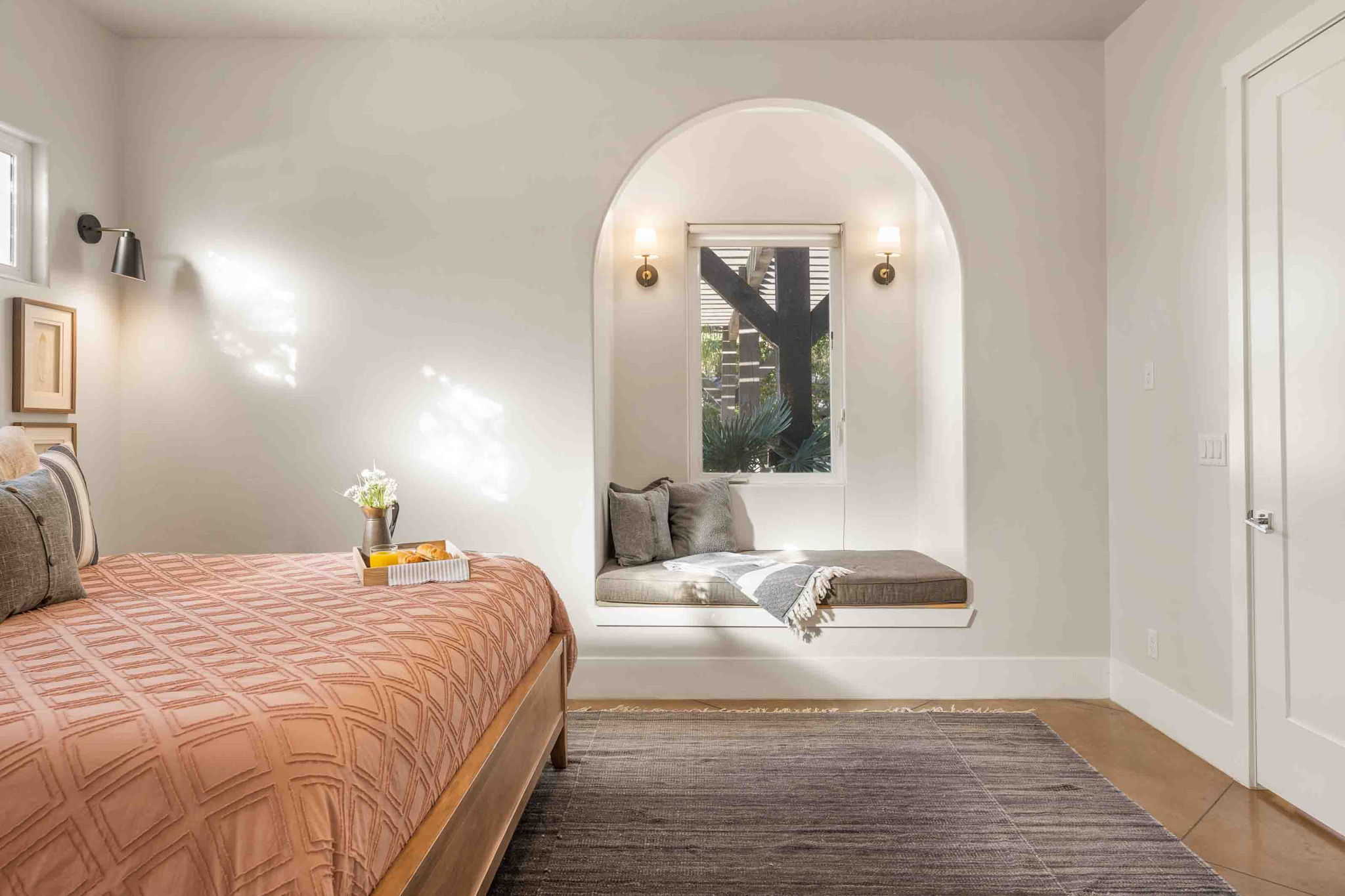 Arched window alcove featuring a built-in window seat, flanked by sconce lighting