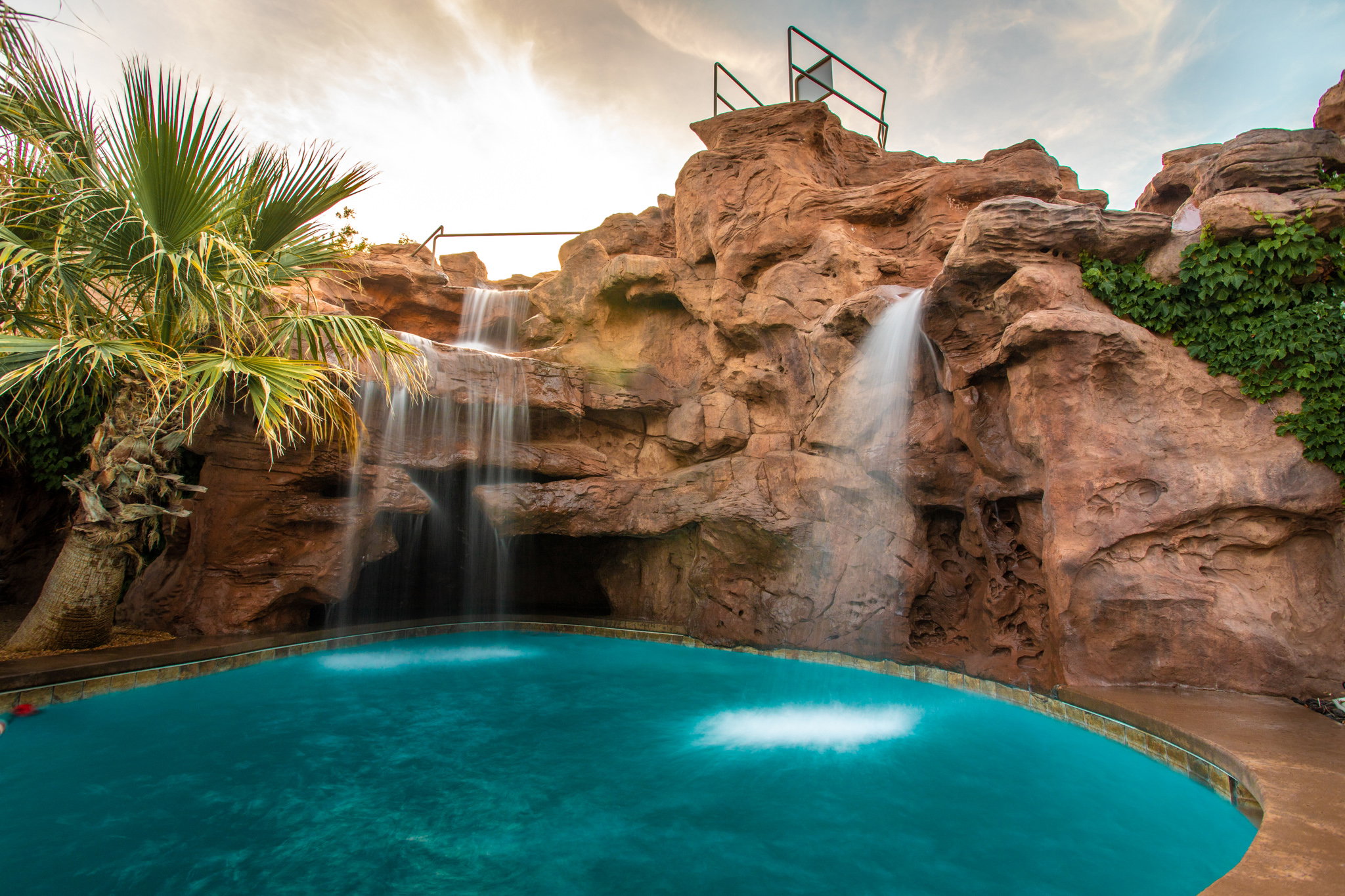 Outdoor pool with rock grotto and dual cascading waterfalls