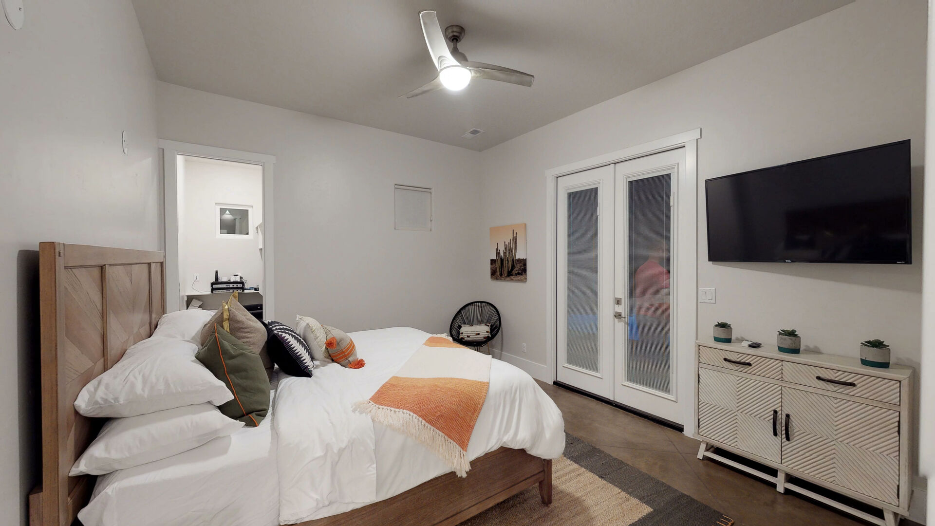 Bedroom featuring a ceiling fan with integrated lighting, a light wood-finish bed frame, and French patio doors with frosted glass panels