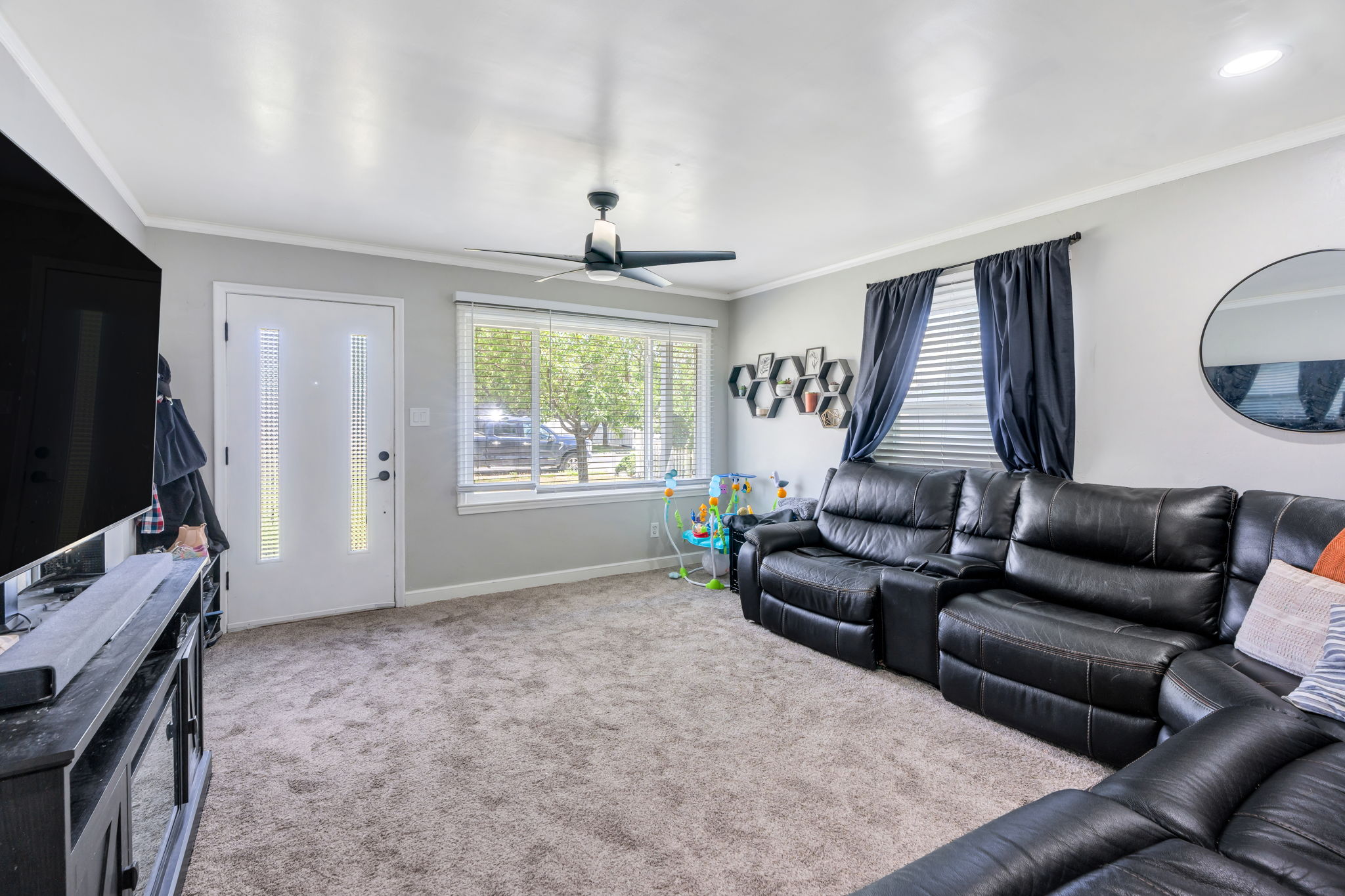 Living area featuring carpet flooring, a ceiling fan, and a front entry door with vertical glass inserts