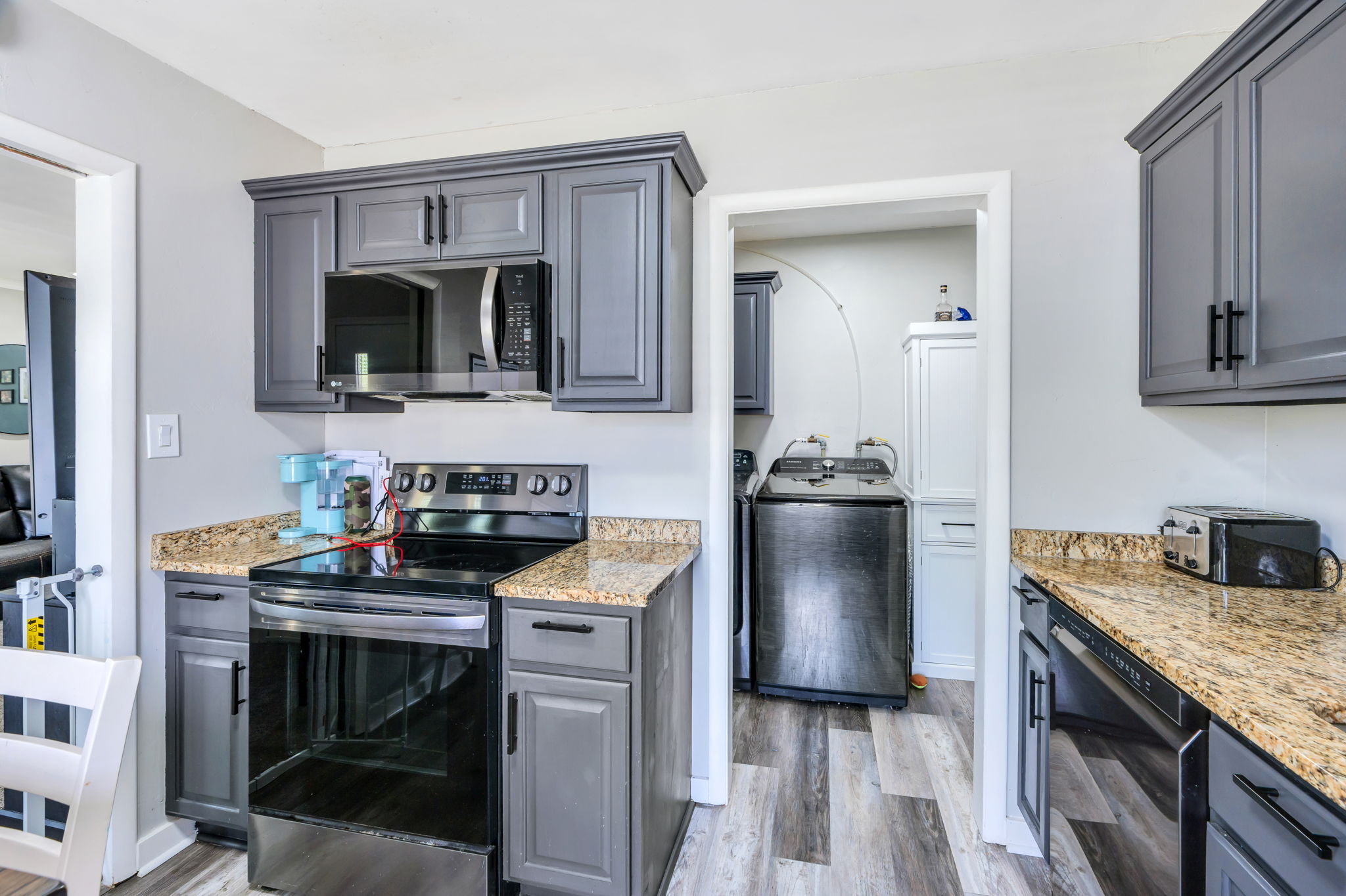 Kitchen featuring gray cabinetry with black hardware, stone-finish countertops, and stainless steel appliances