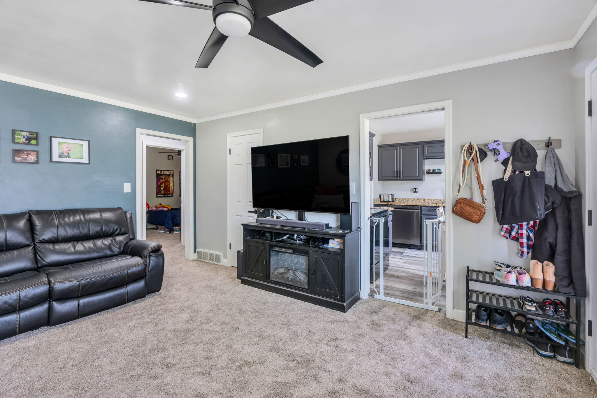 Spacious living area featuring neutral carpeting, a modern ceiling fan, and crisp white trim