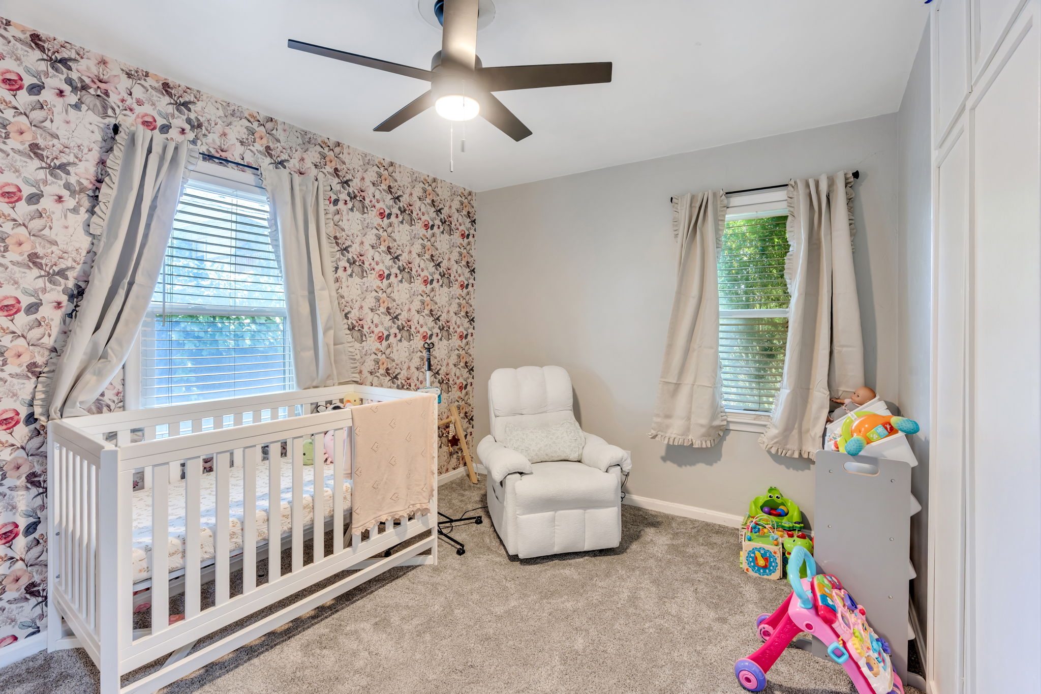 Room featuring a floral accent wall, light grey painted walls, and grey carpeting