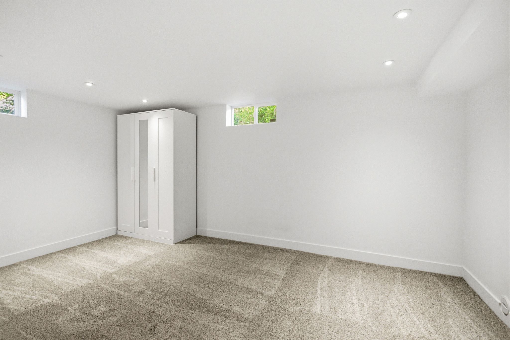 Finished room featuring light-toned carpeting, recessed lighting, and bright white walls