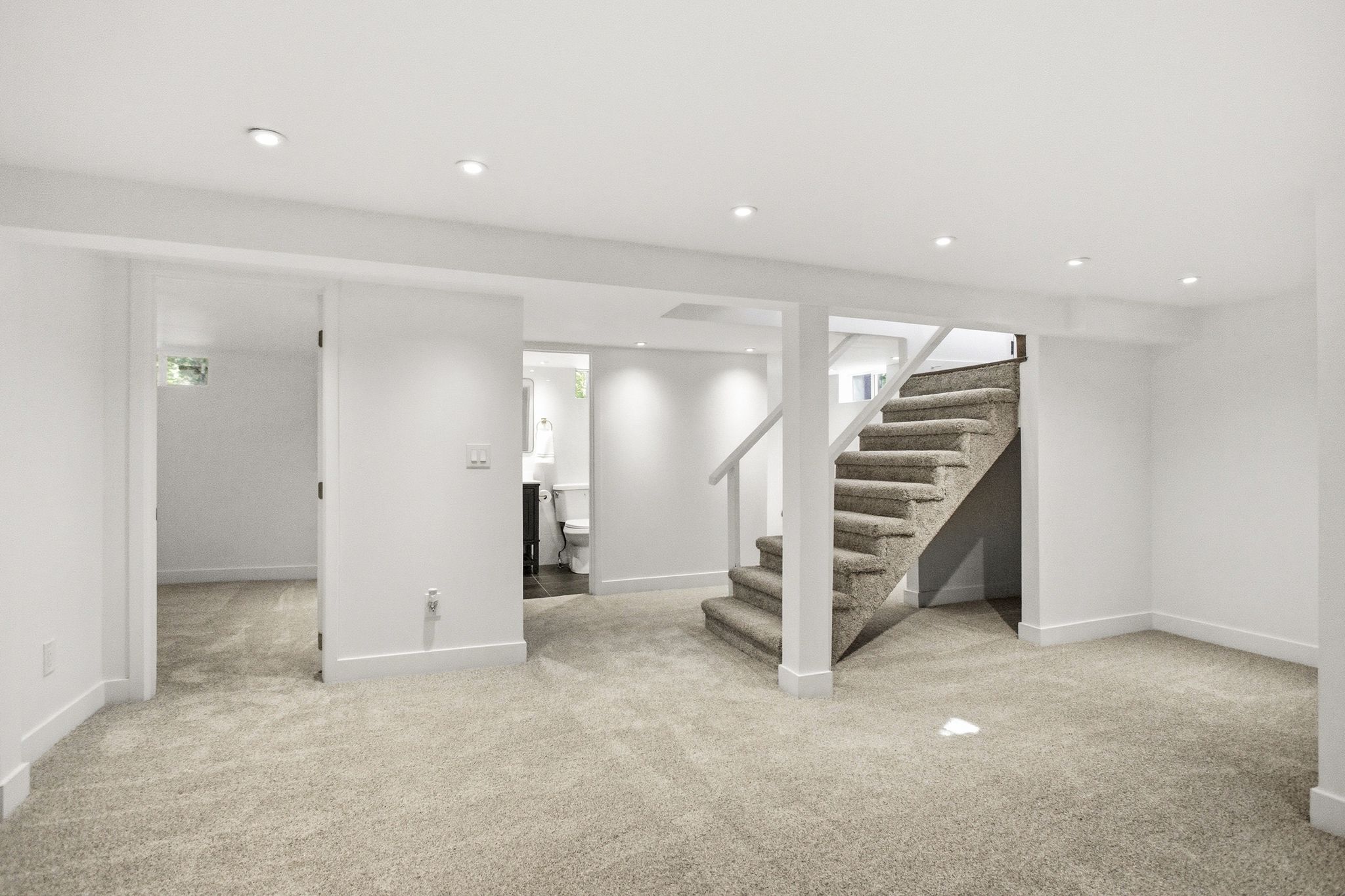 Carpeted lower level with recessed lighting, a carpeted staircase with white railings, and white walls