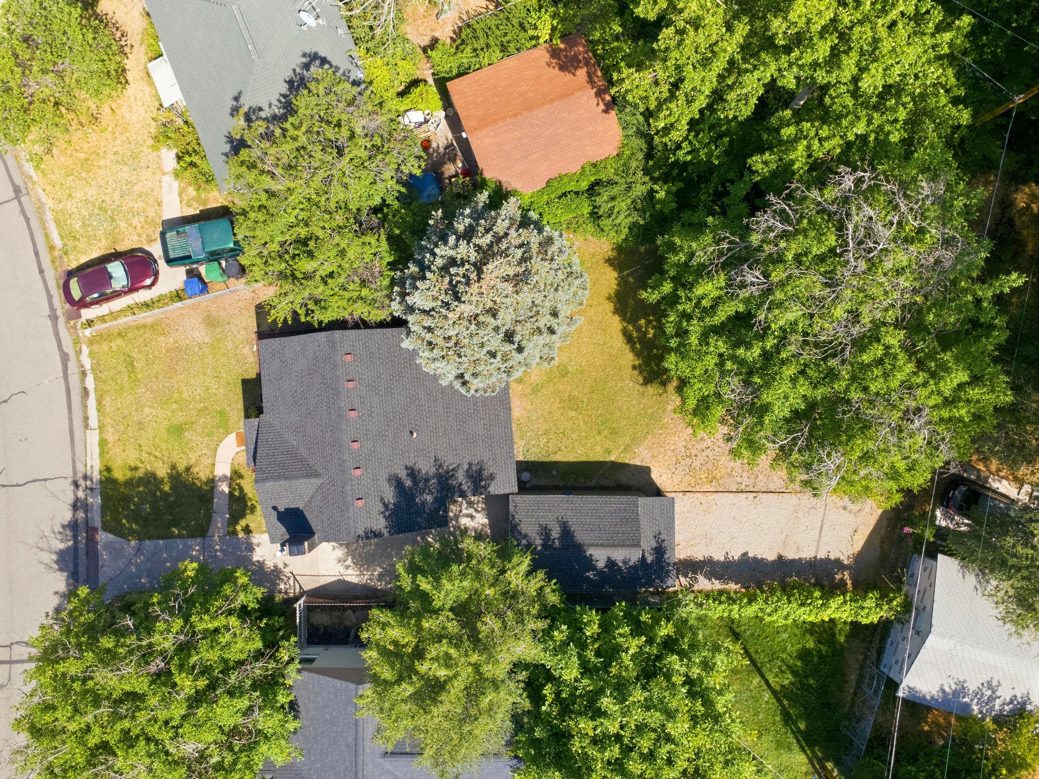Expansive property featuring a dark shingle roof, established landscaping, and a detached outbuilding