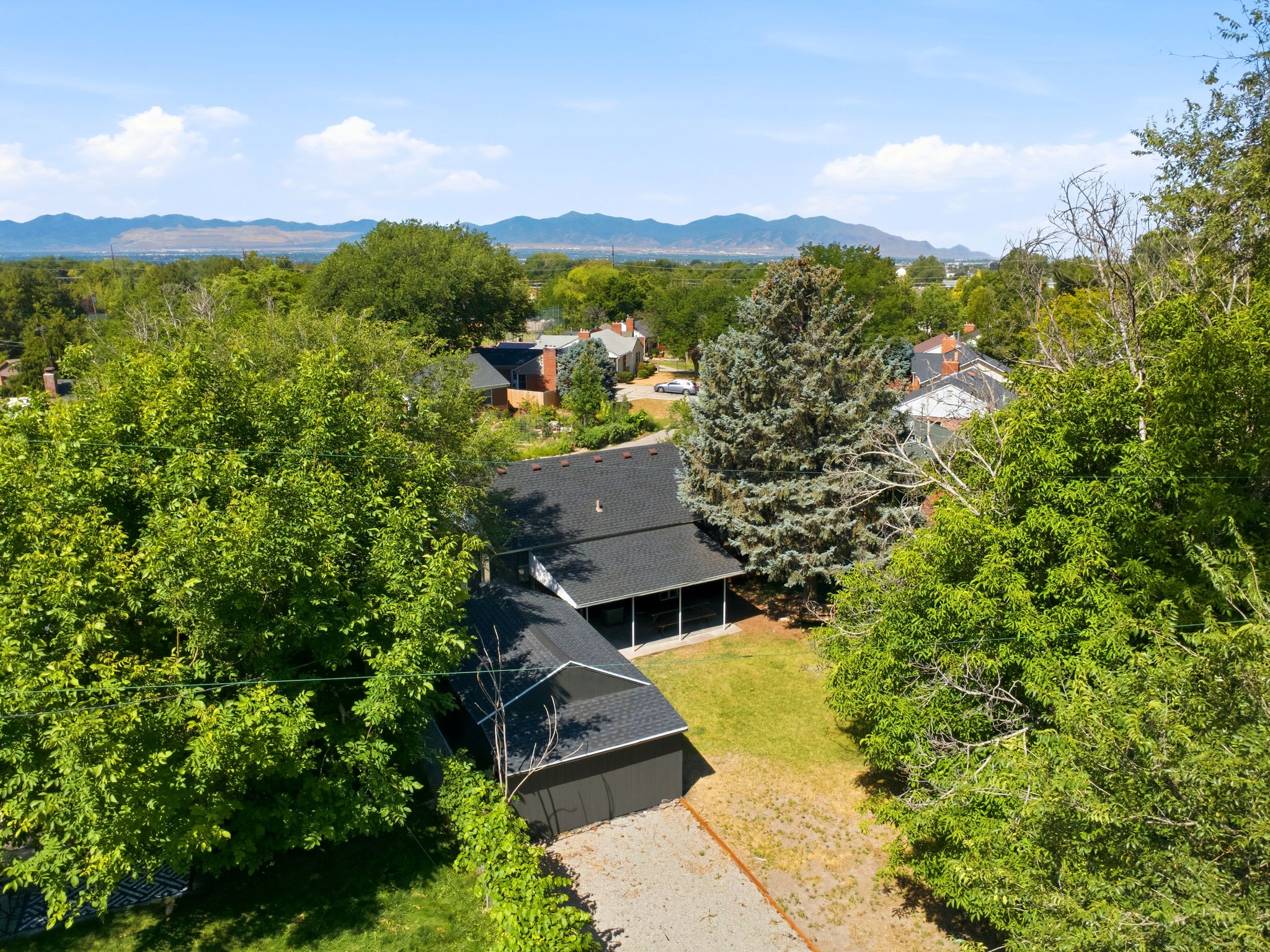 Aerial property view featuring a dark-toned roof, a covered patio area, and a detached garage with a matching roofline