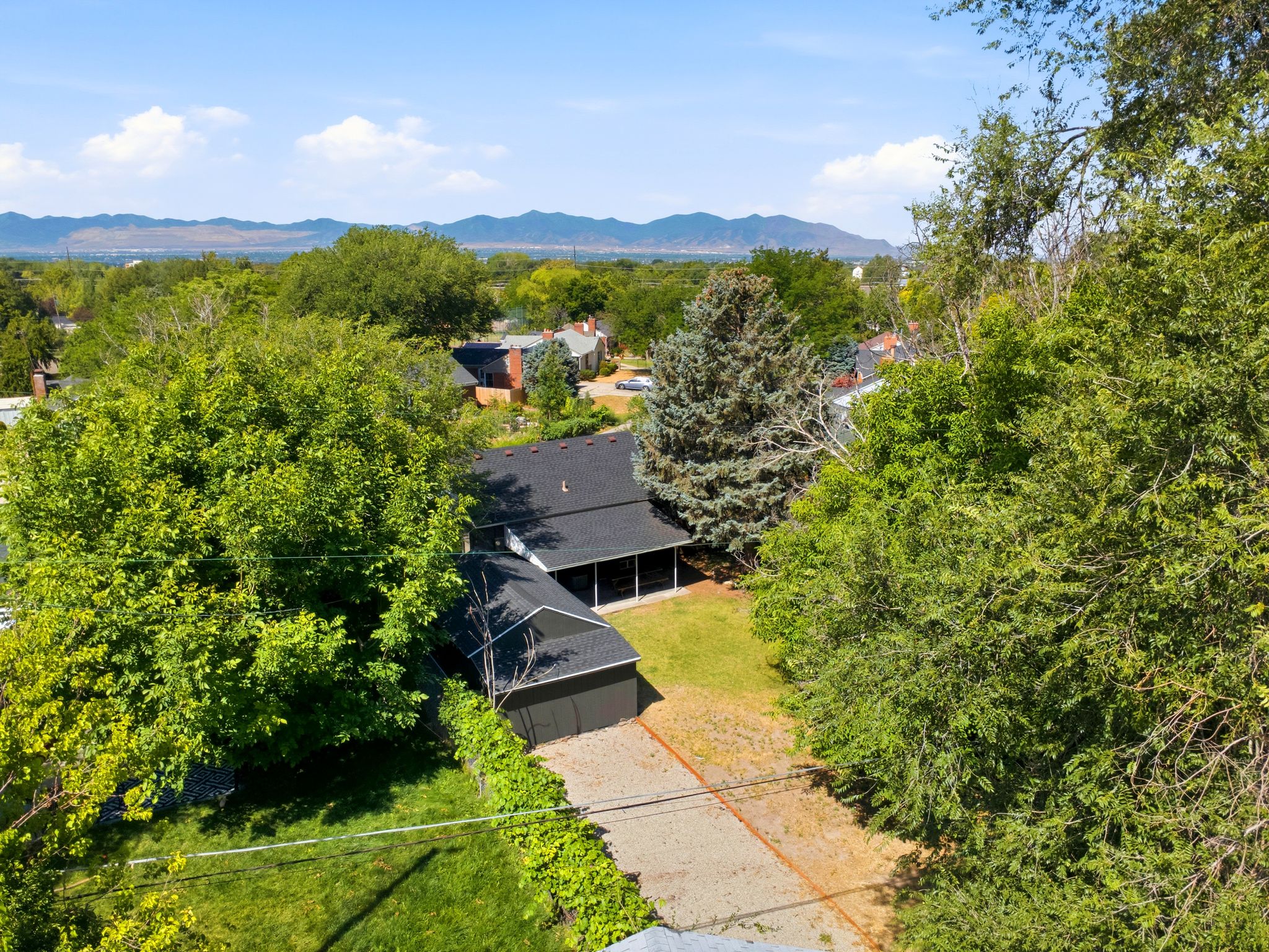 Aerial perspective showcasing a residential property with a detached garage, lush green lawn, and mature trees
