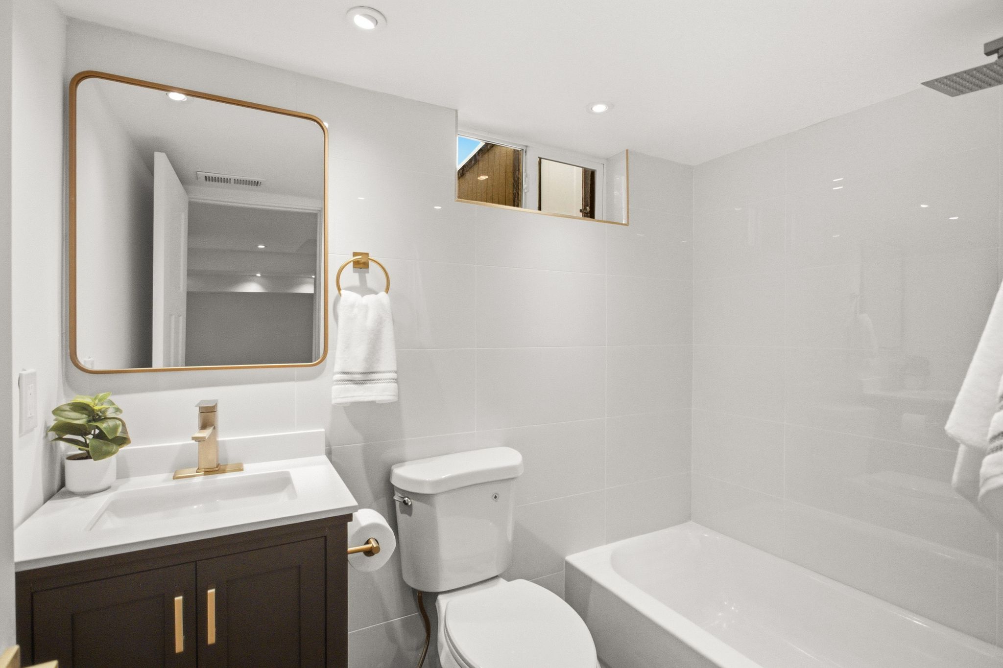 Bathroom featuring a modern vanity with dark wood-finish cabinetry, a white countertop, and gold-tone fixtures